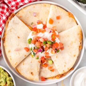 quesadillas on a plate topped with sour cream and pico
