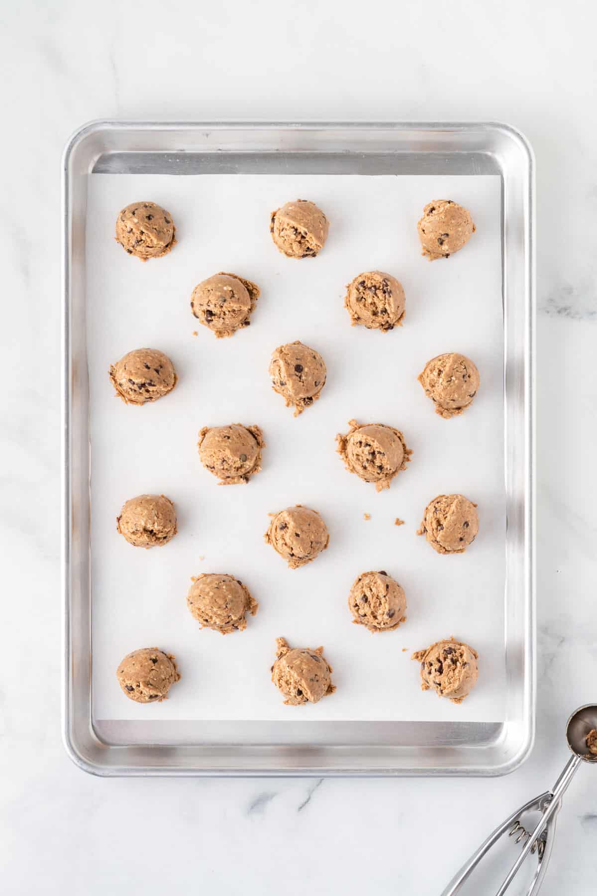 scoops of energy ball batter on a lined baking sheet