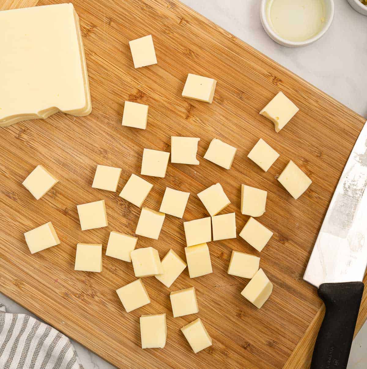 cutting american cheese into blocks on a cutting board