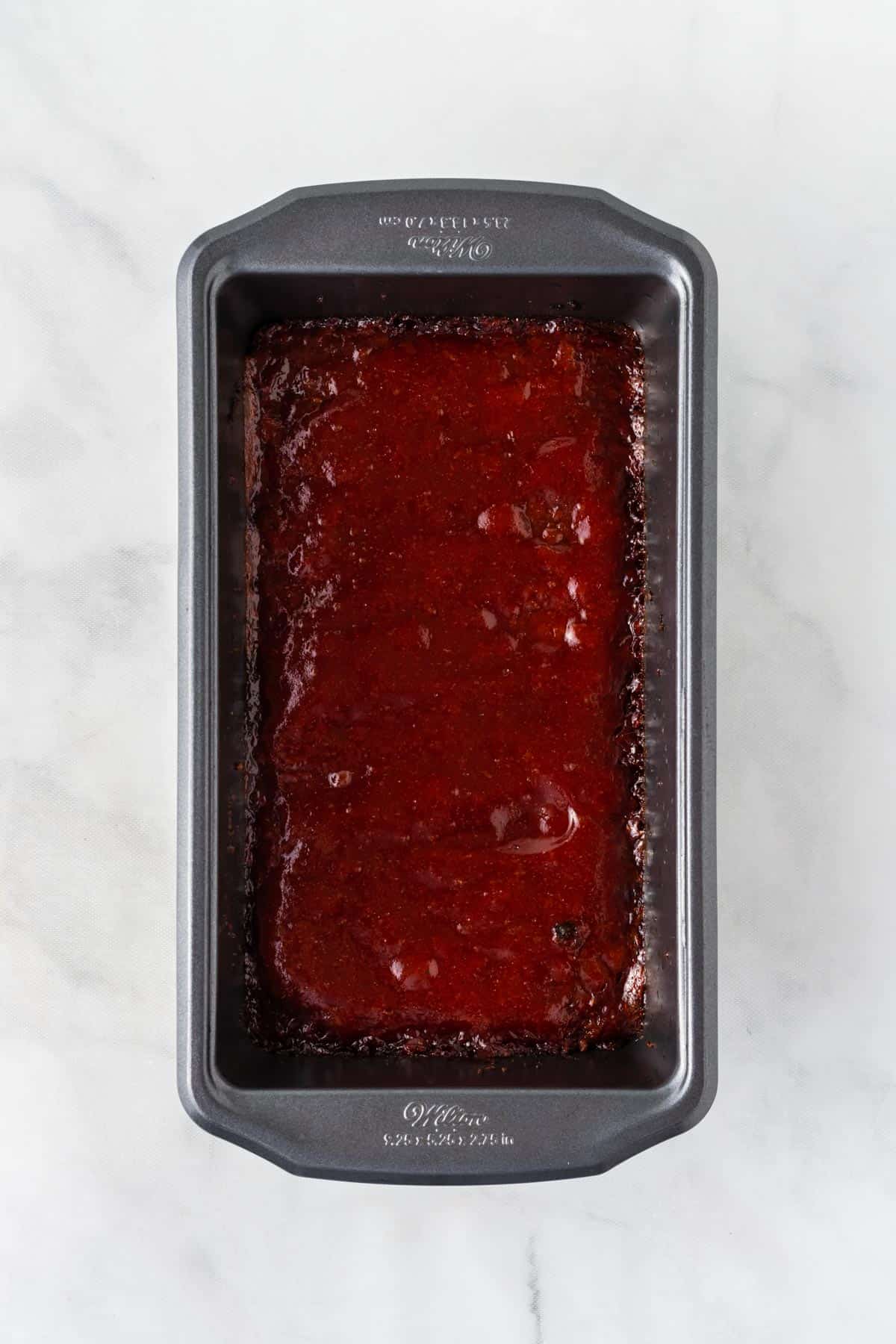 meatloaf in the pan topped with the brown sugar ketchup glaze