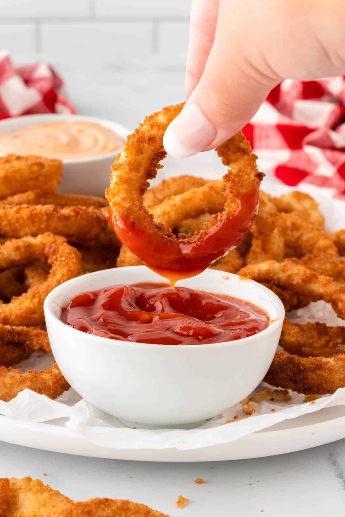 dipping an onion ring into ketchup