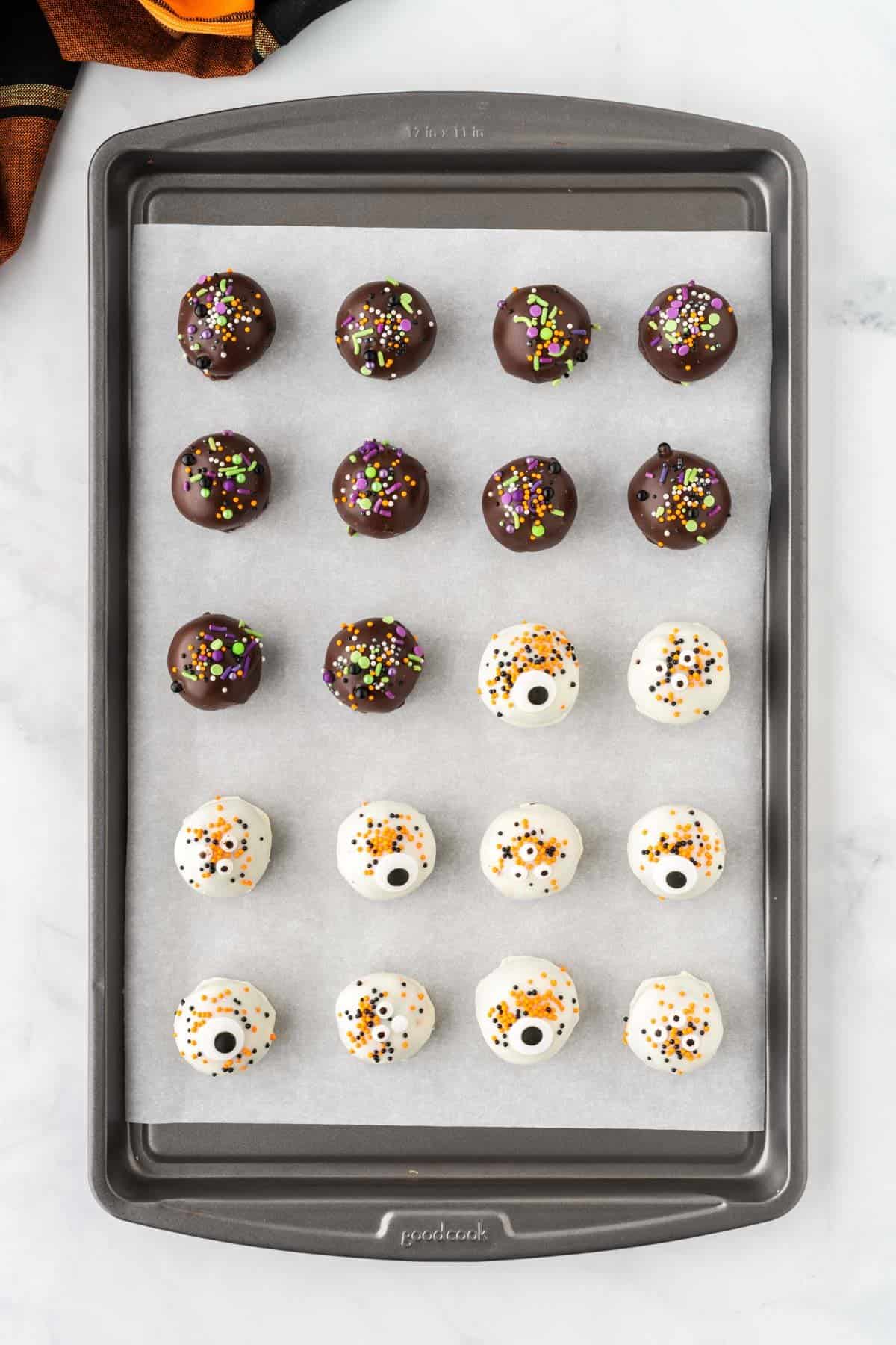 oreo balls on a lined baking sheet decorated with halloween sprinkles