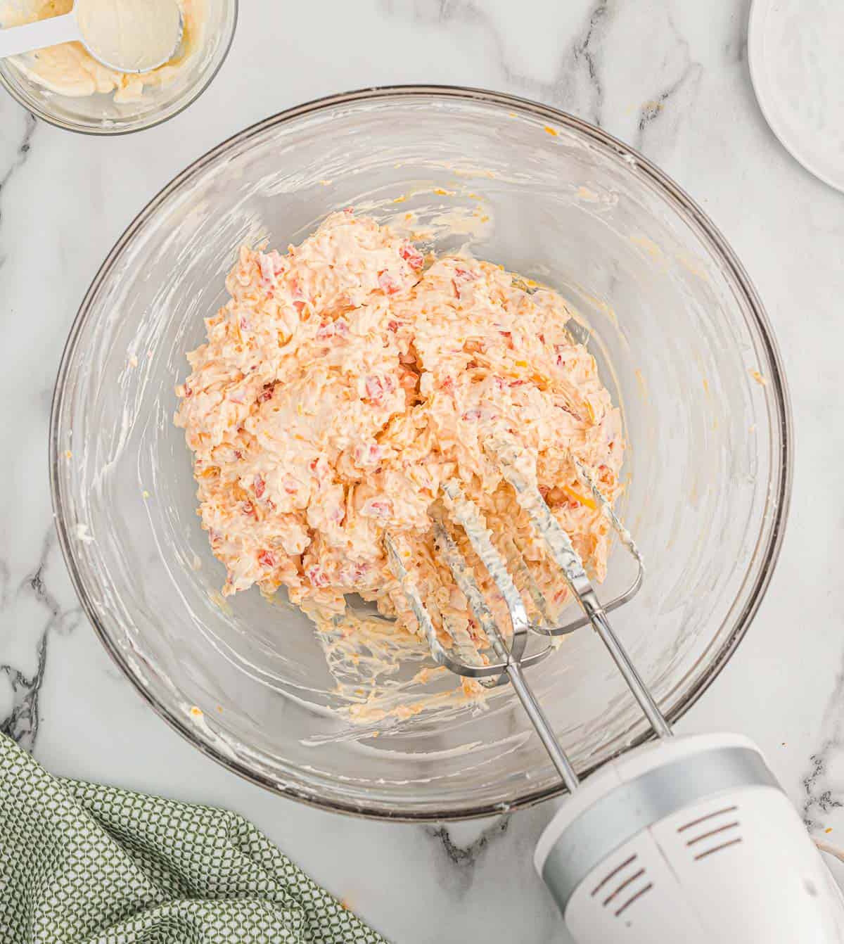 mixing the pimento cheese in a glass bowl