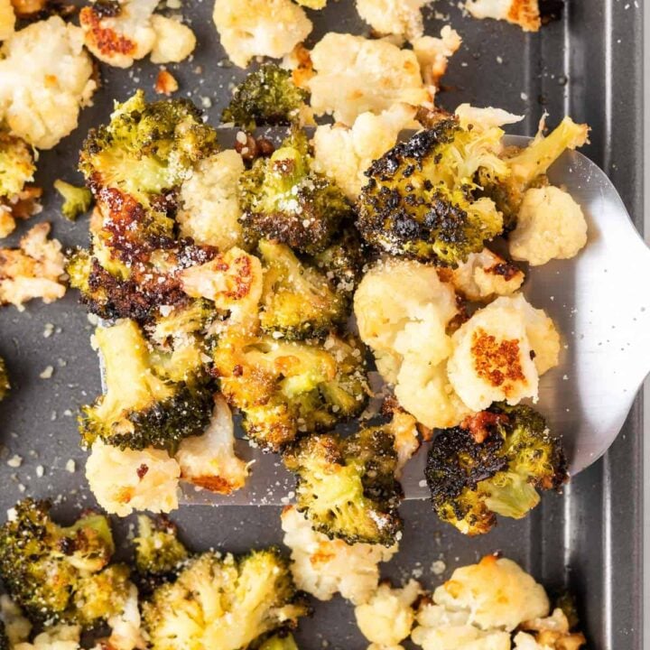 spatula taking roasted broccoli and cauliflower from the pan