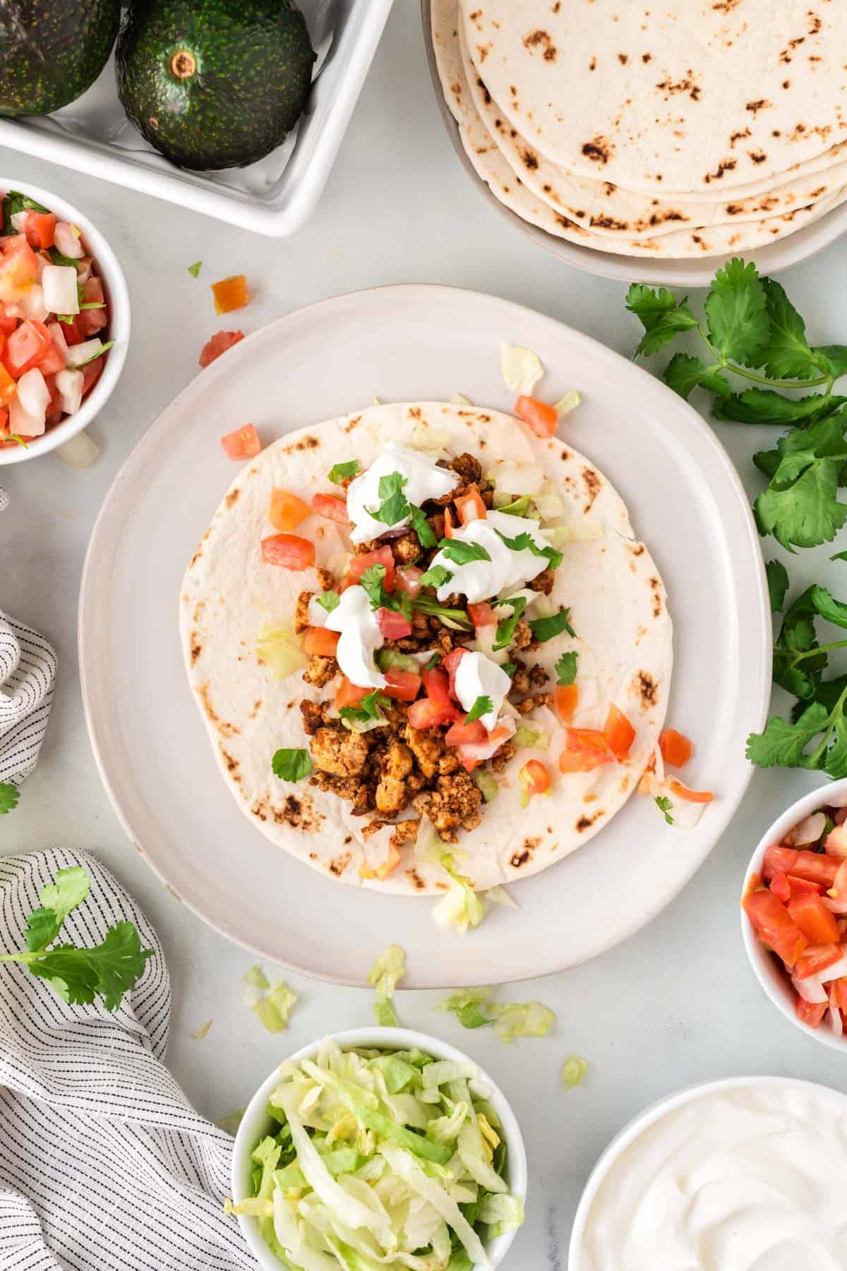 tofu taco topped with sour cream, cilantro, and tomatoes