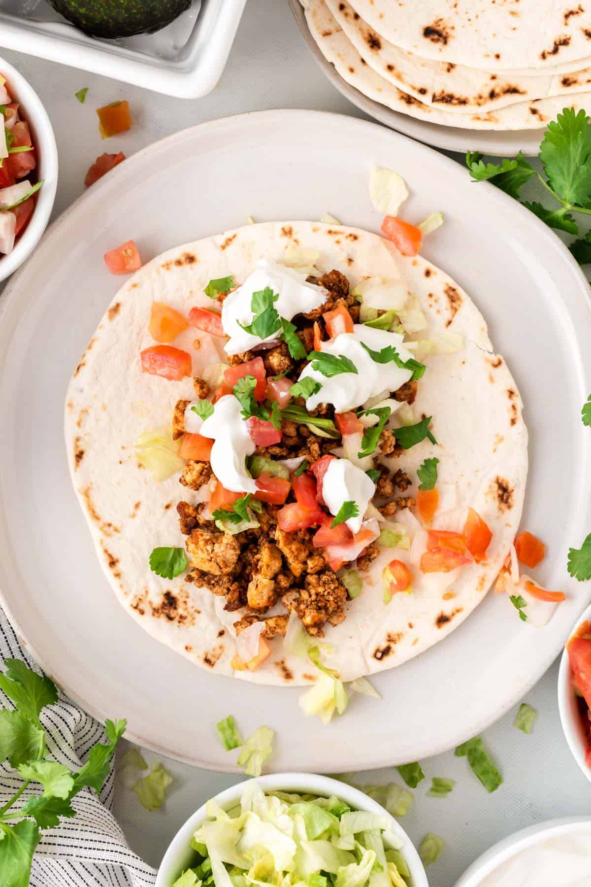 tofu taco topped with sour cream, cilantro, and tomatoes