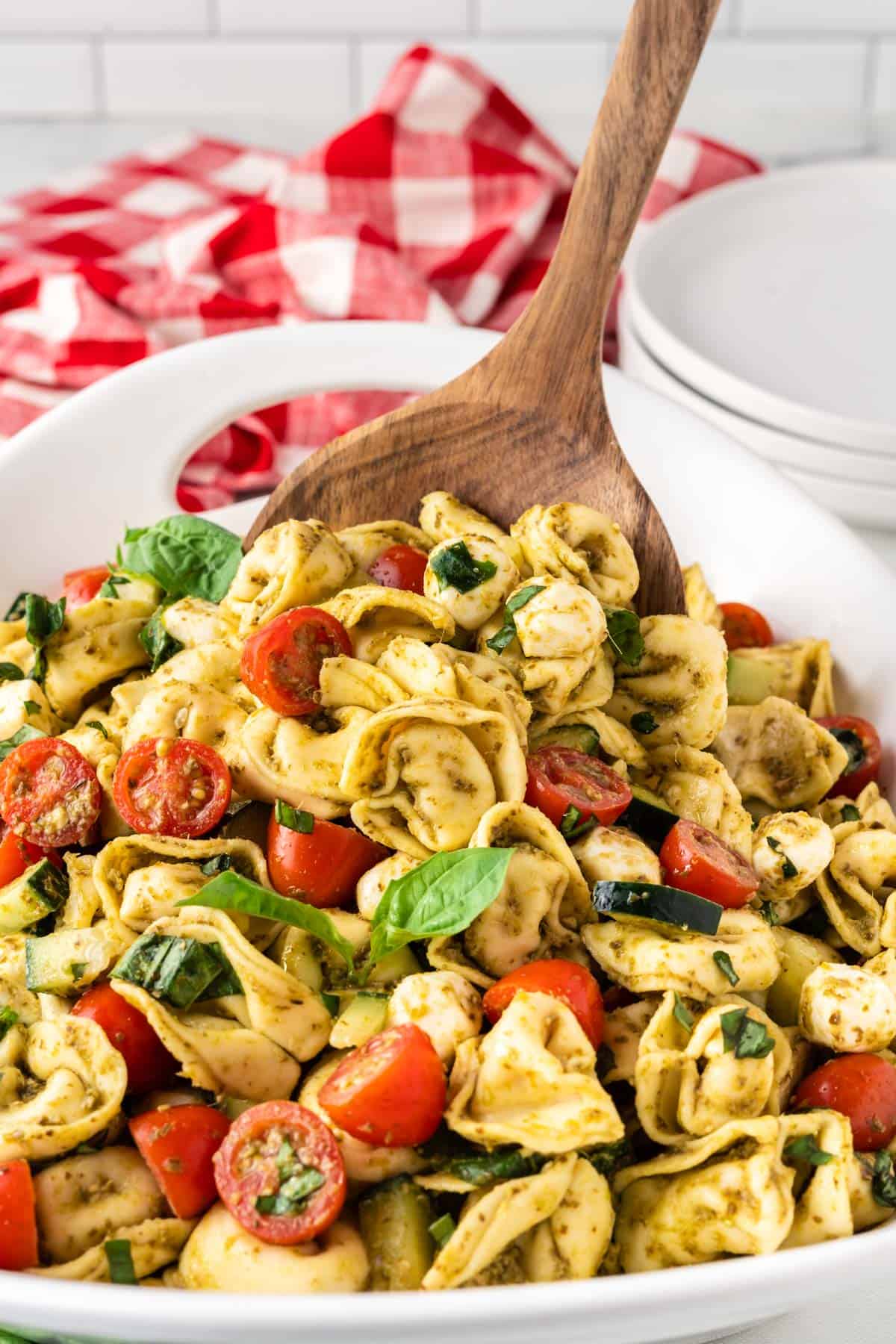 serving tortellini pasta salad with a wooden spoon