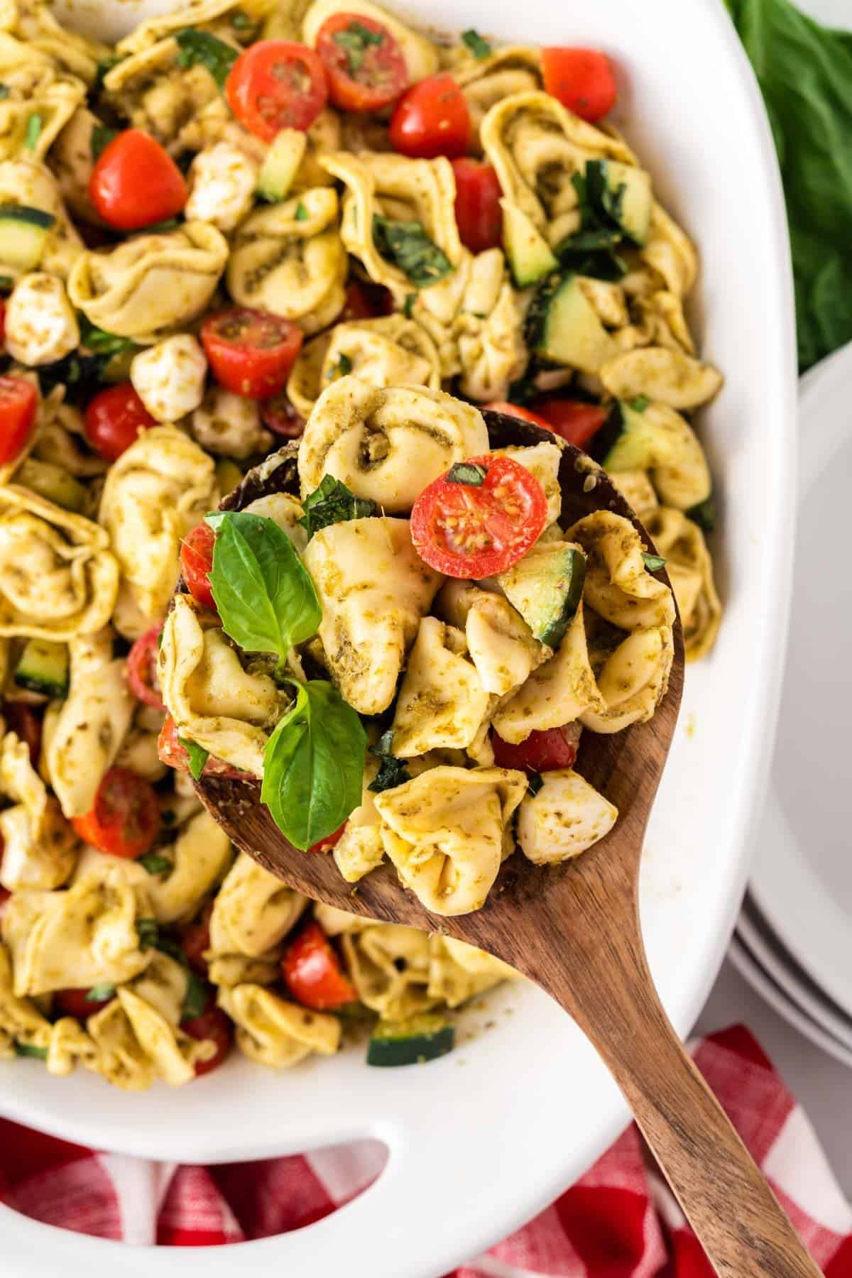 serving tortellini pasta salad with a wooden spoon