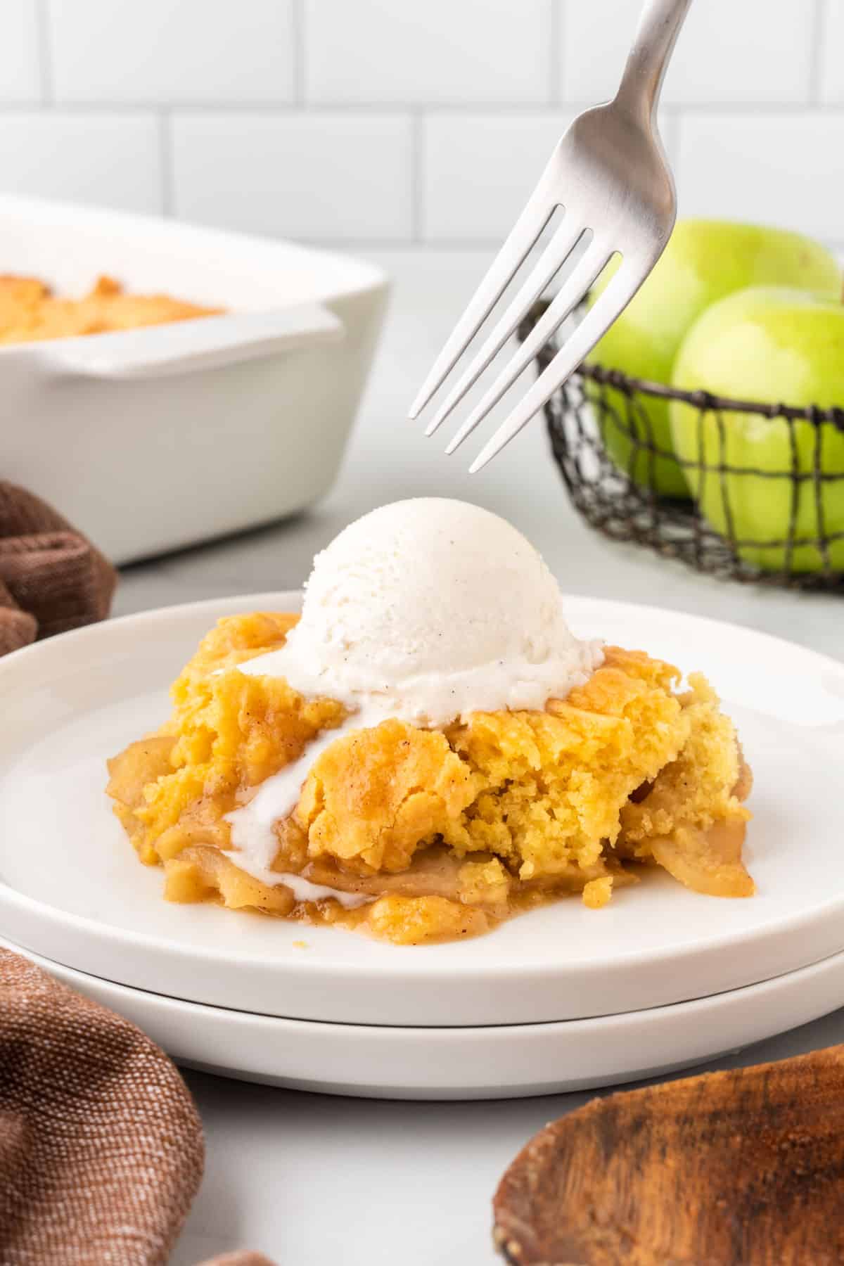 apple cobbler on a plate topped with vanilla ice cream