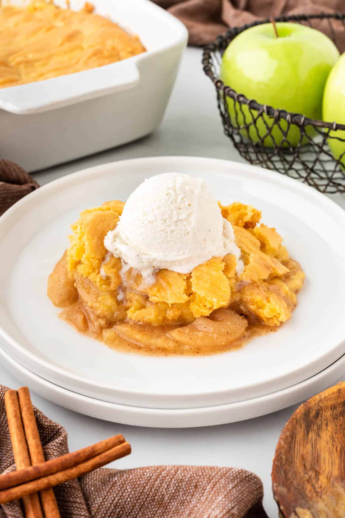 apple cobbler on a plate topped with vanilla ice cream