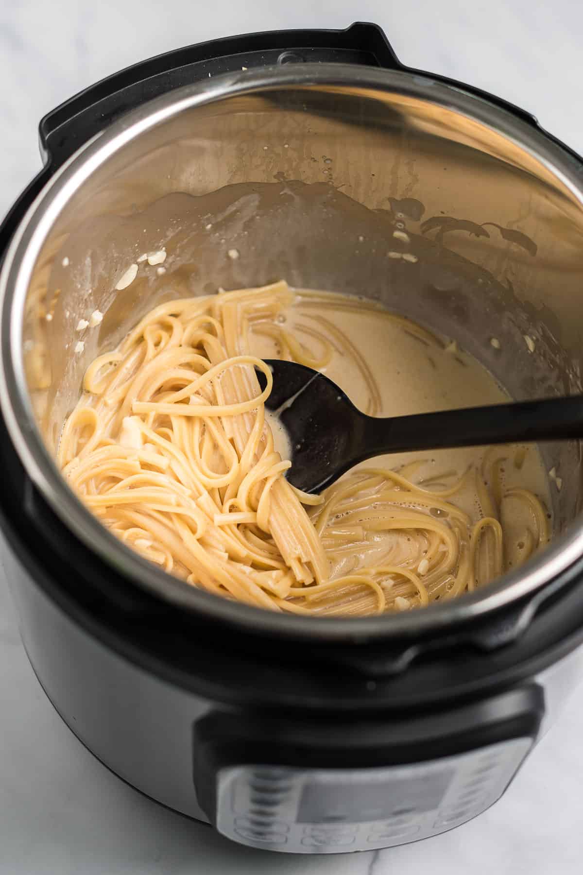 stirring the noodles into the cream sauce