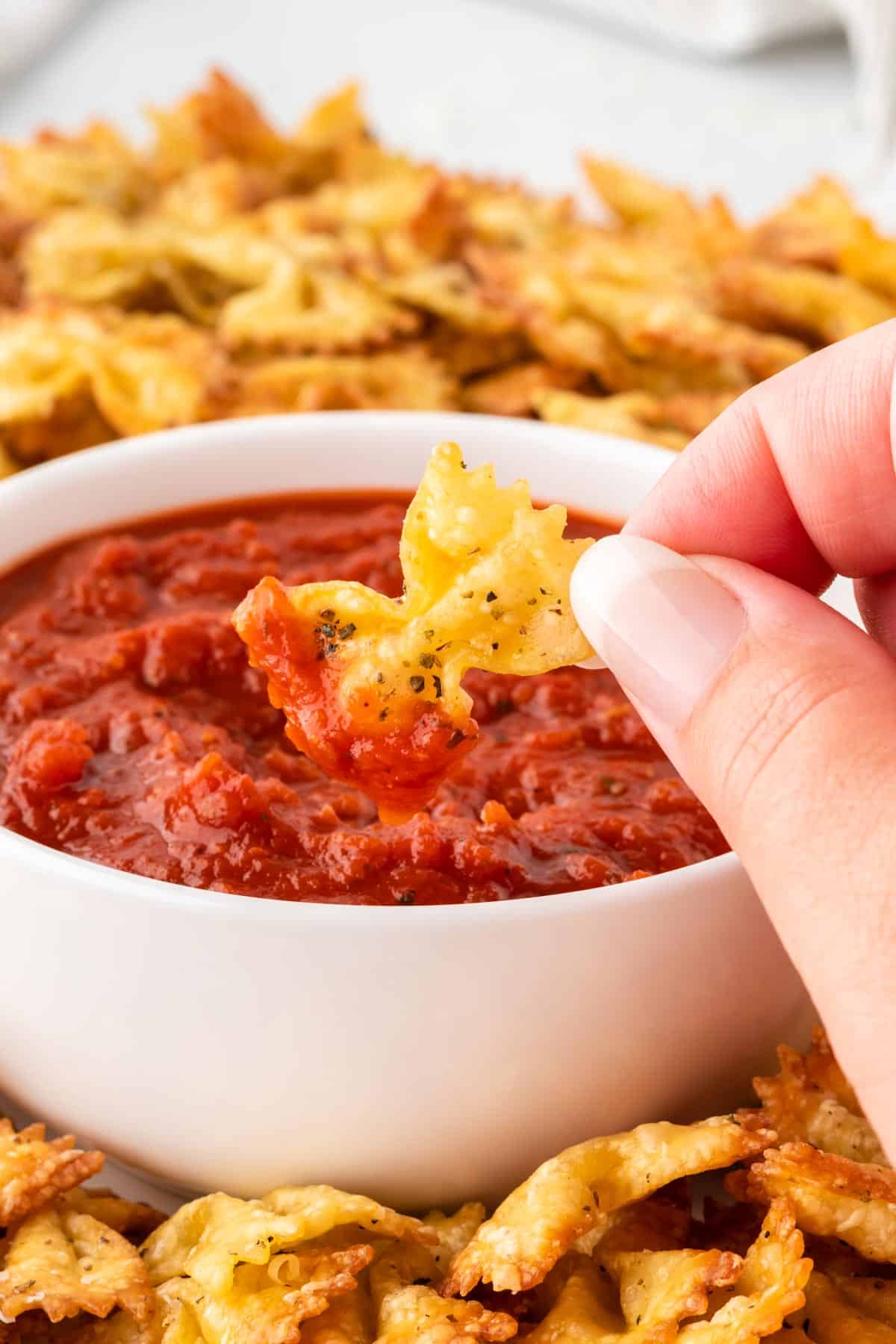 dipping a pasta chip into marinara