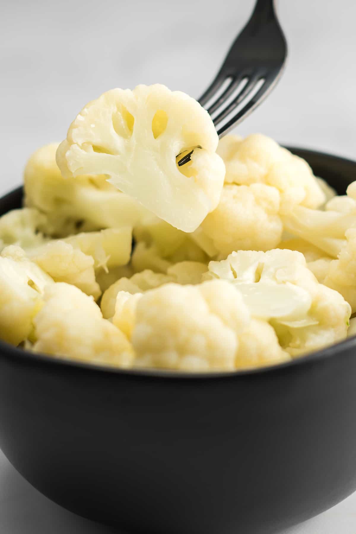 fork taking a floret of cauliflower from a bowl