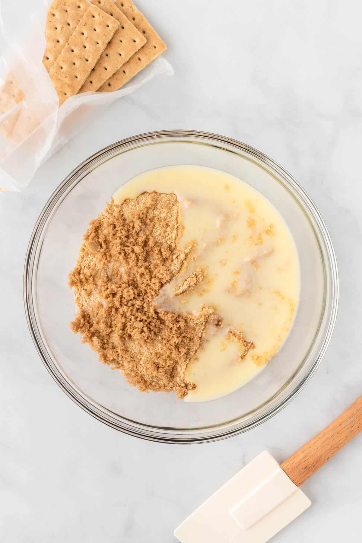 melted butter and crushed graham crackers in a bowl