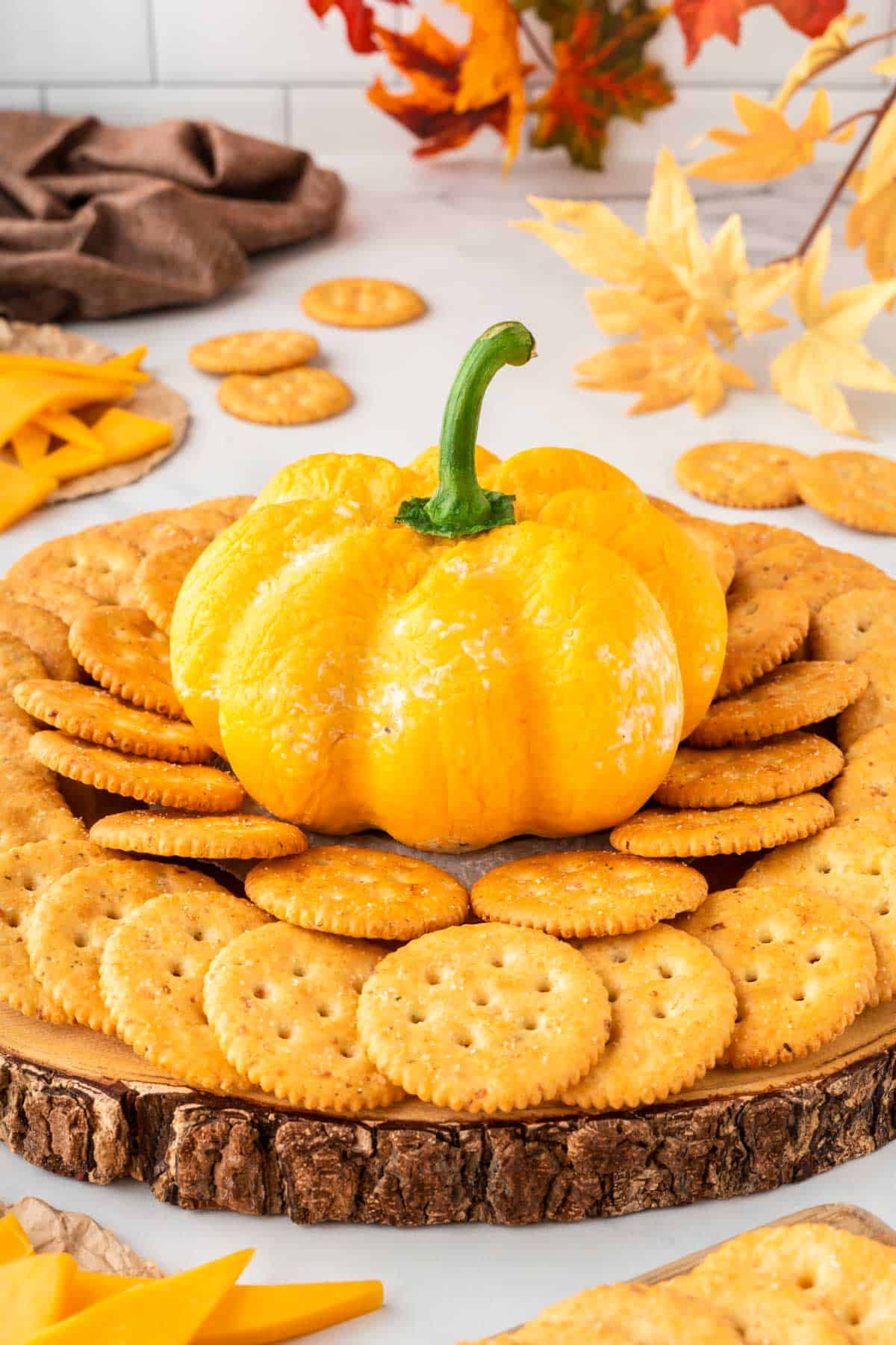 pumpkin shaped cheese ball surrounded by crackers for dipping