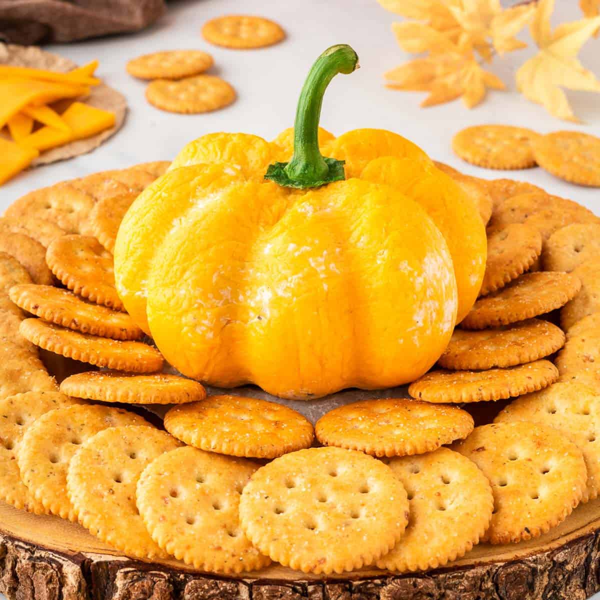 pumpkin shaped cheese ball surrounded by crackers for dipping