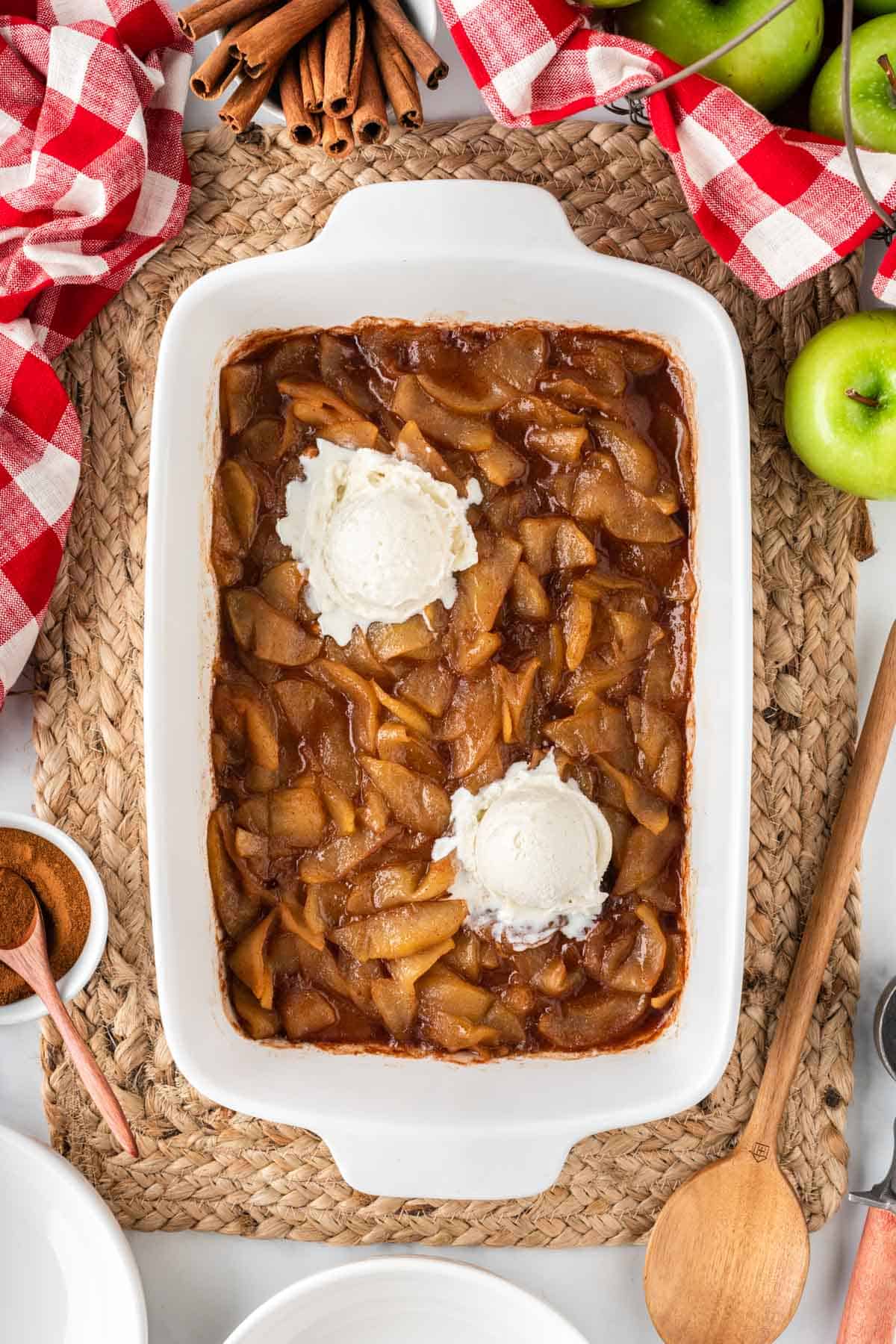 cinnamon apples in a baking dish topped with vanilla ice cream