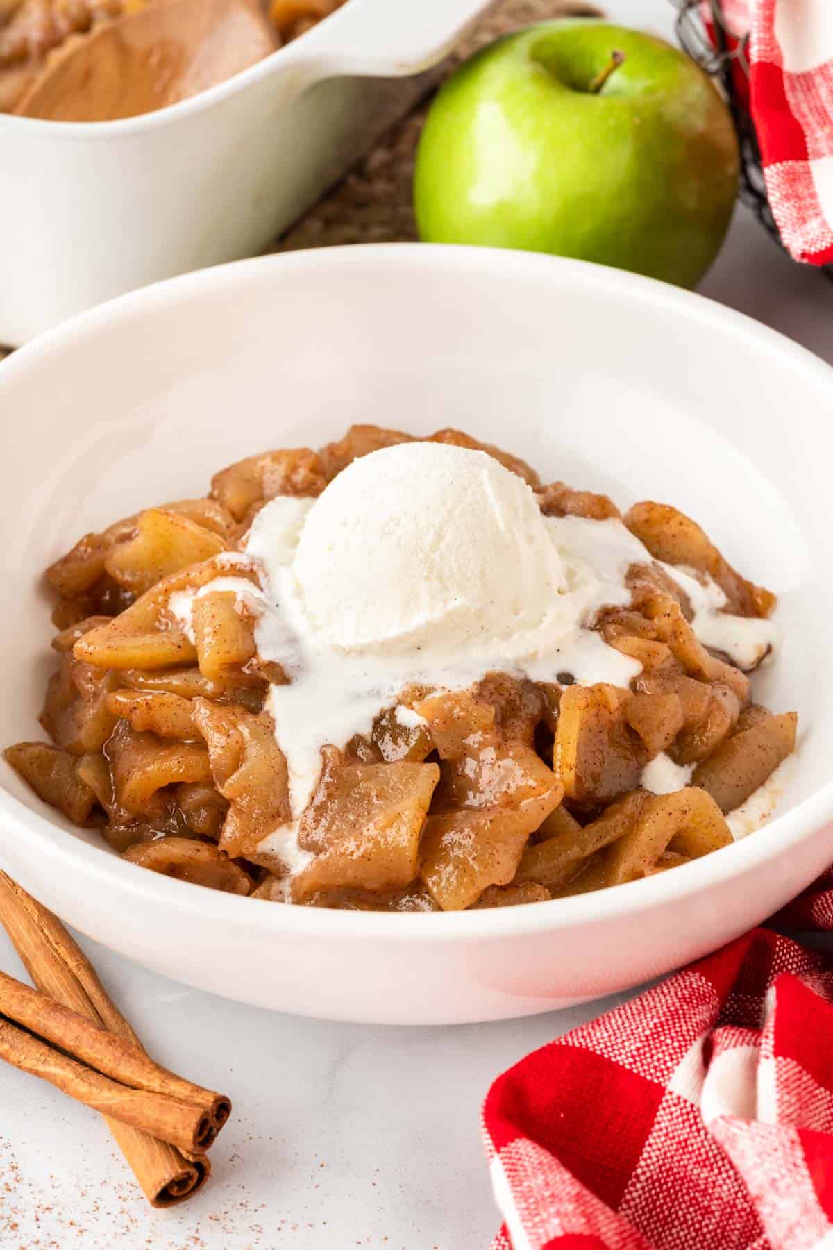 cinnamon apples in a bowl topped with a scoop of vanilla ice cream