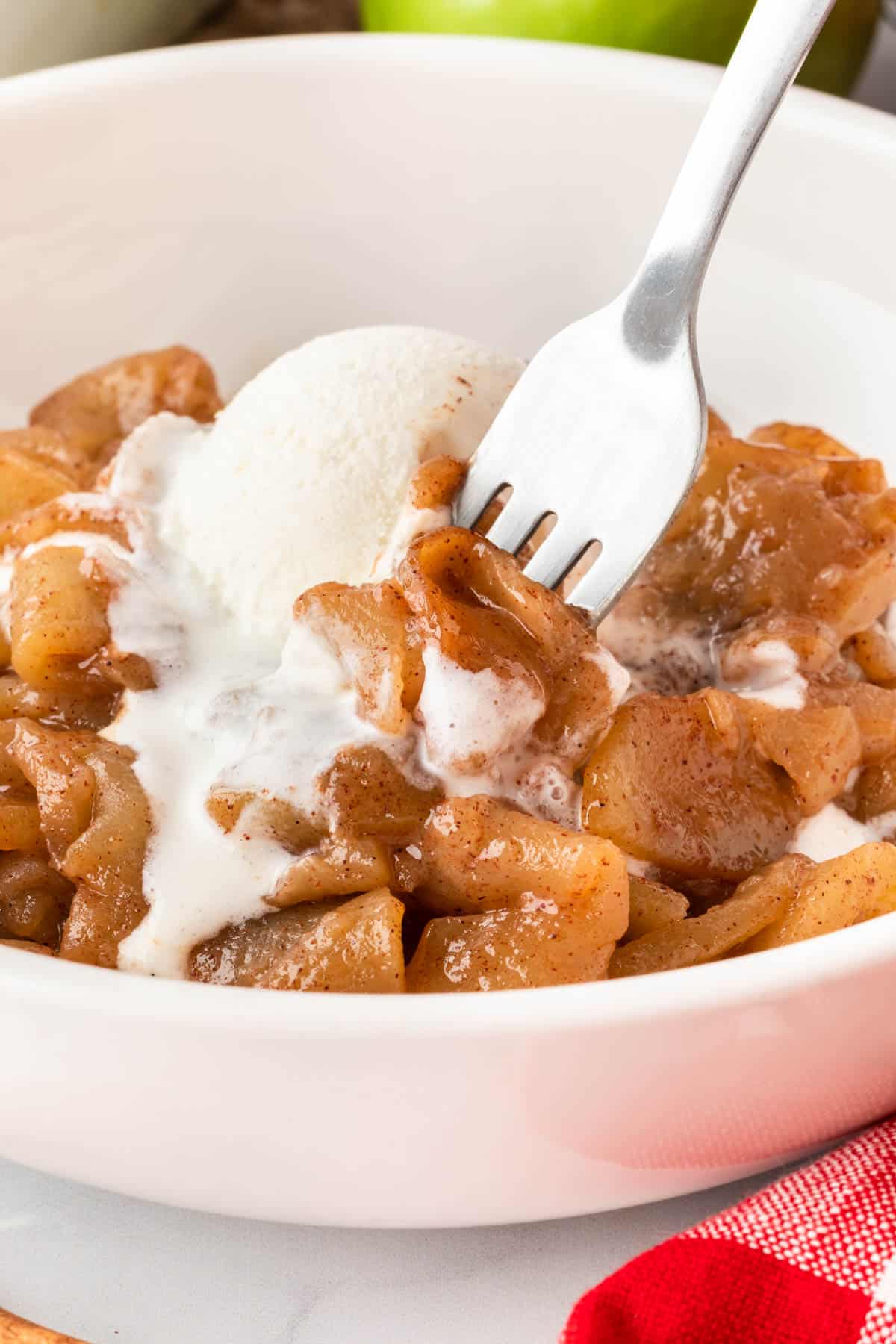 fork taking a bite of cinnamon apples with ice cream