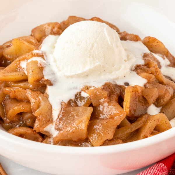 cinnamon apples in a bowl topped with a scoop of vanilla ice cream