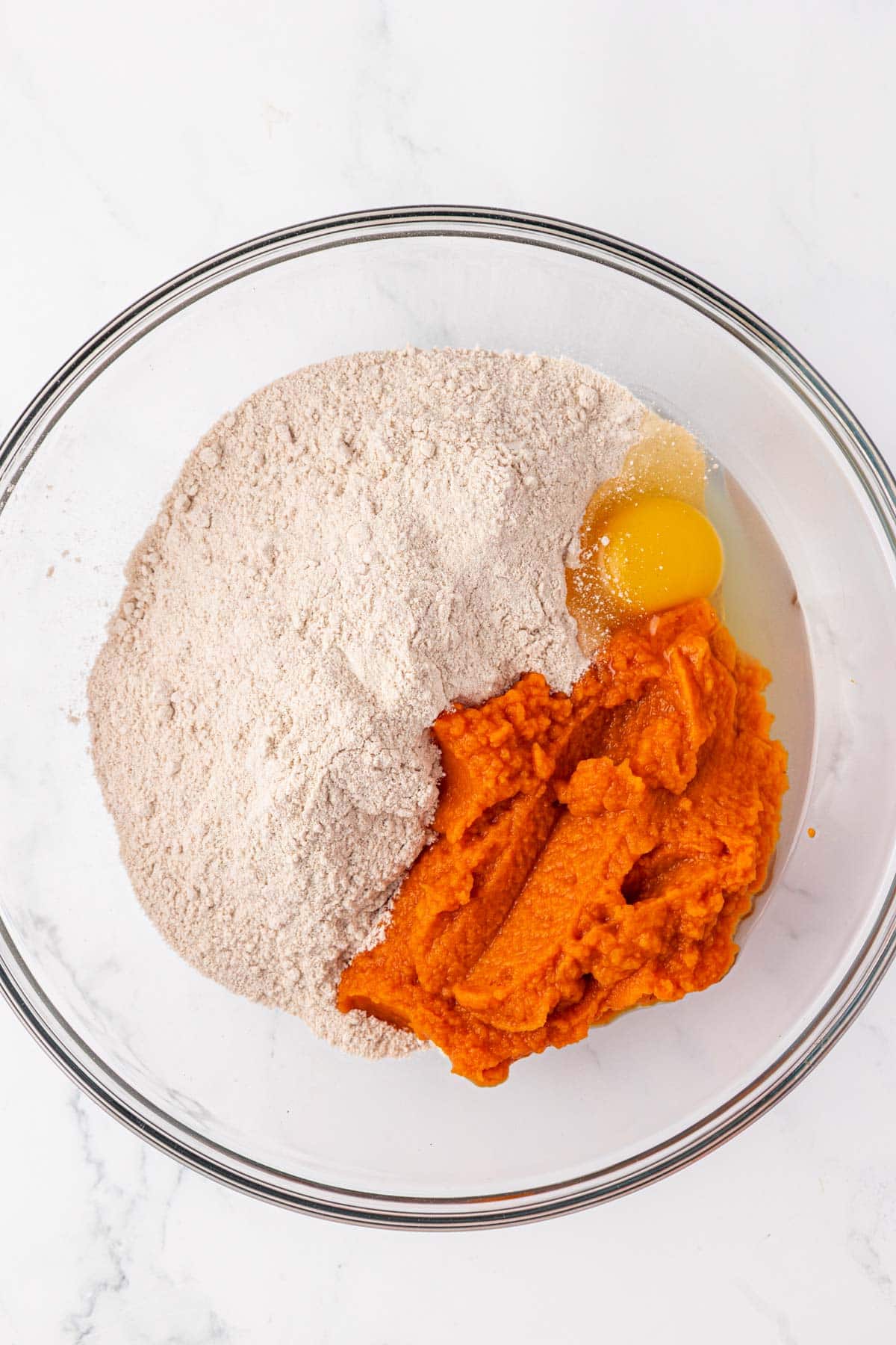 an egg, pumpkin puree, and spice cake mix in a bowl