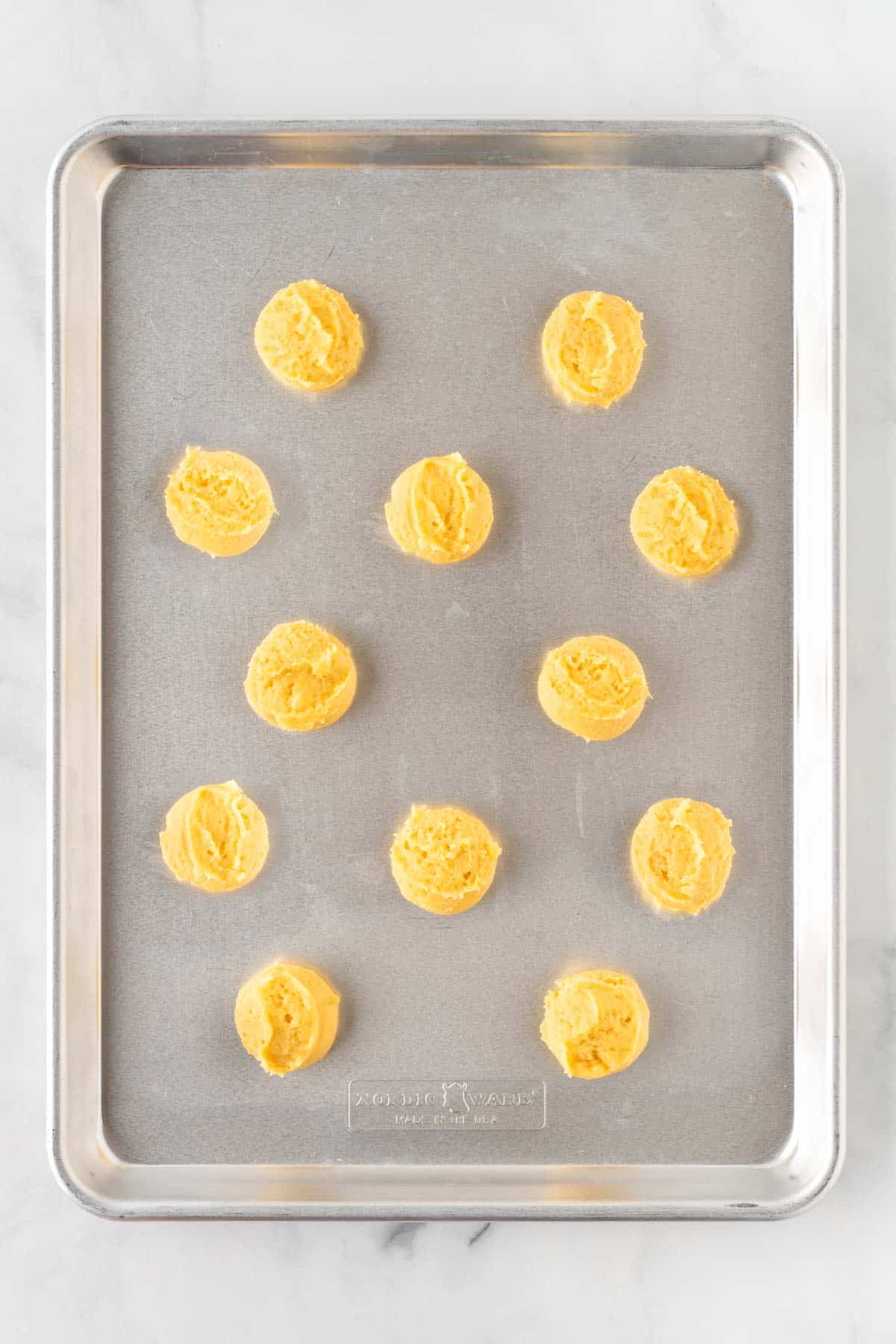 sugar cookie dough balls on a baking sheet