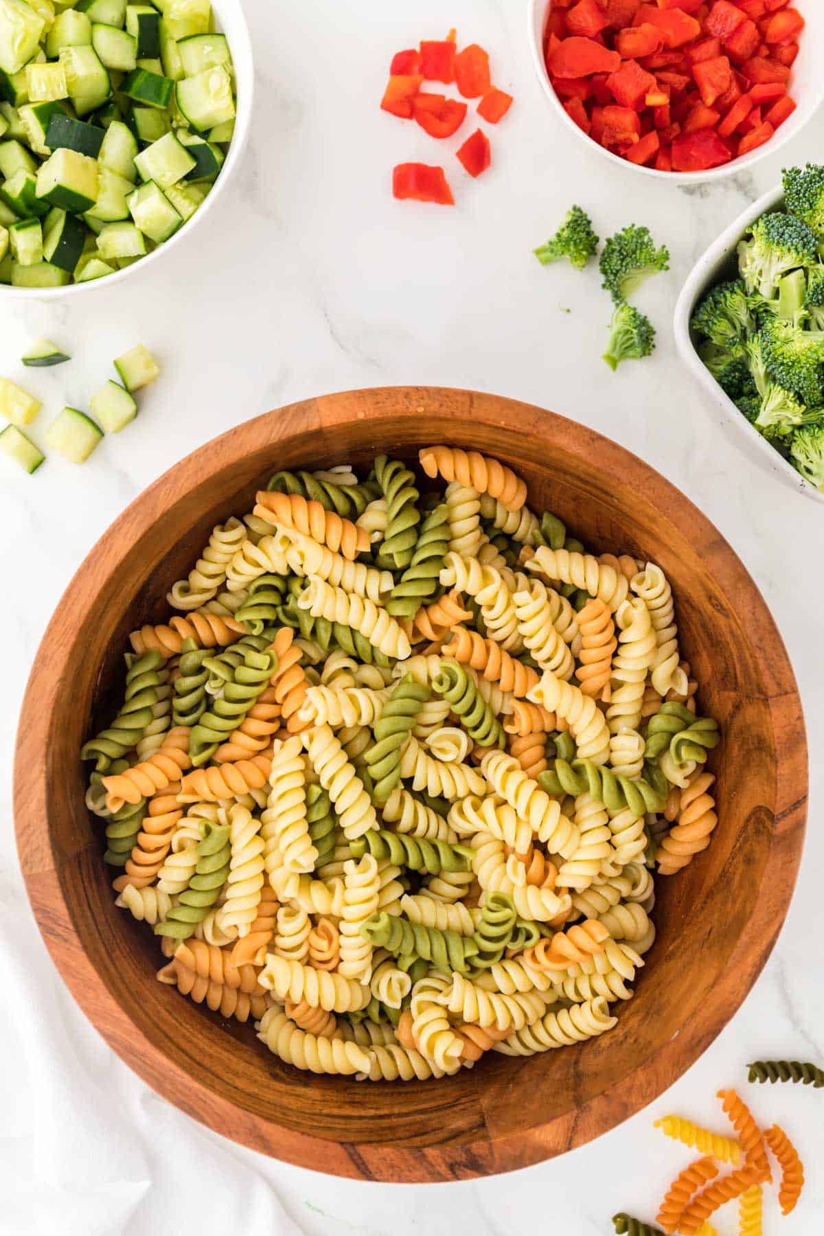 cooked tri color rotini in a wooden bowl