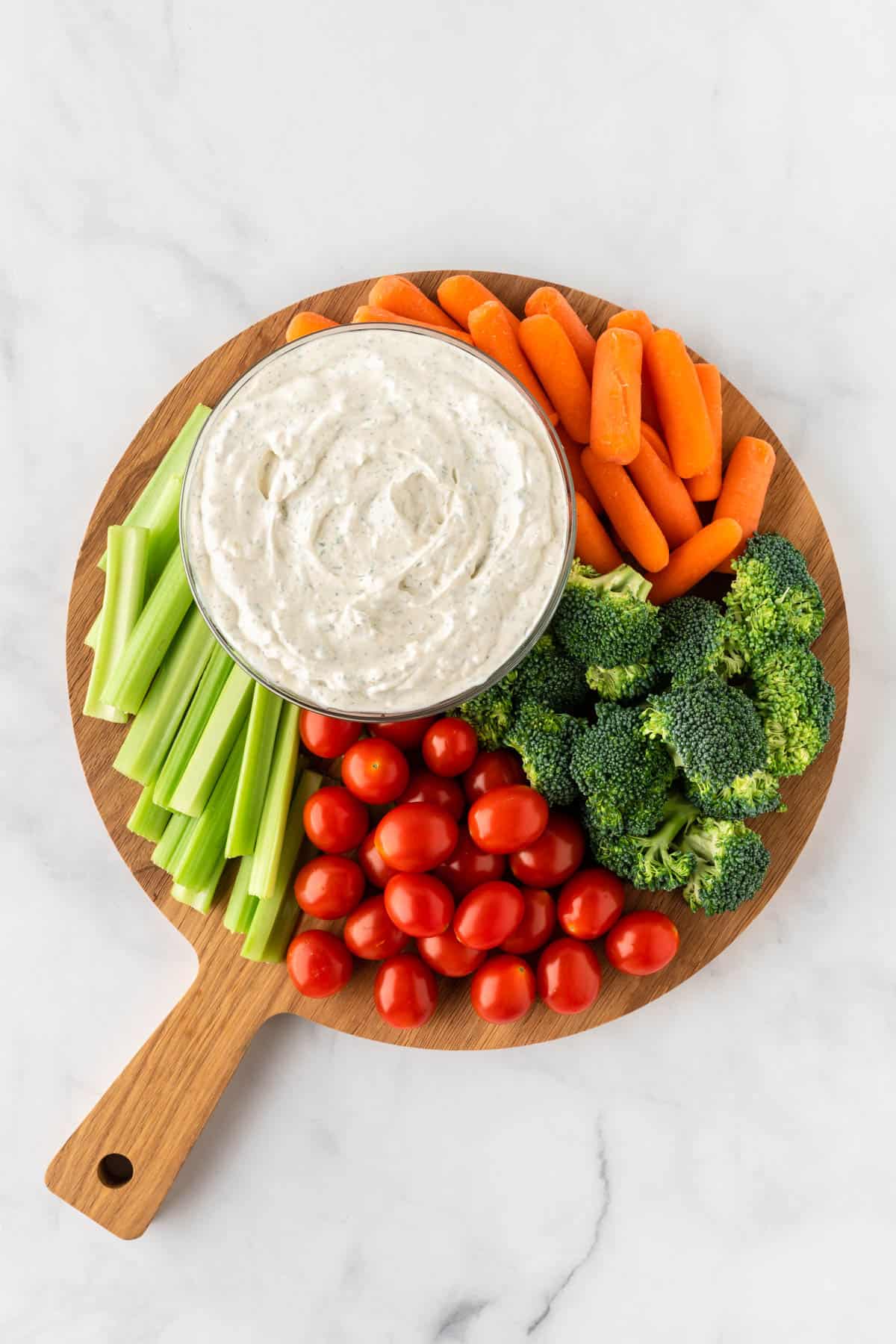 cutting board with fresh cut veggies and veggie dip