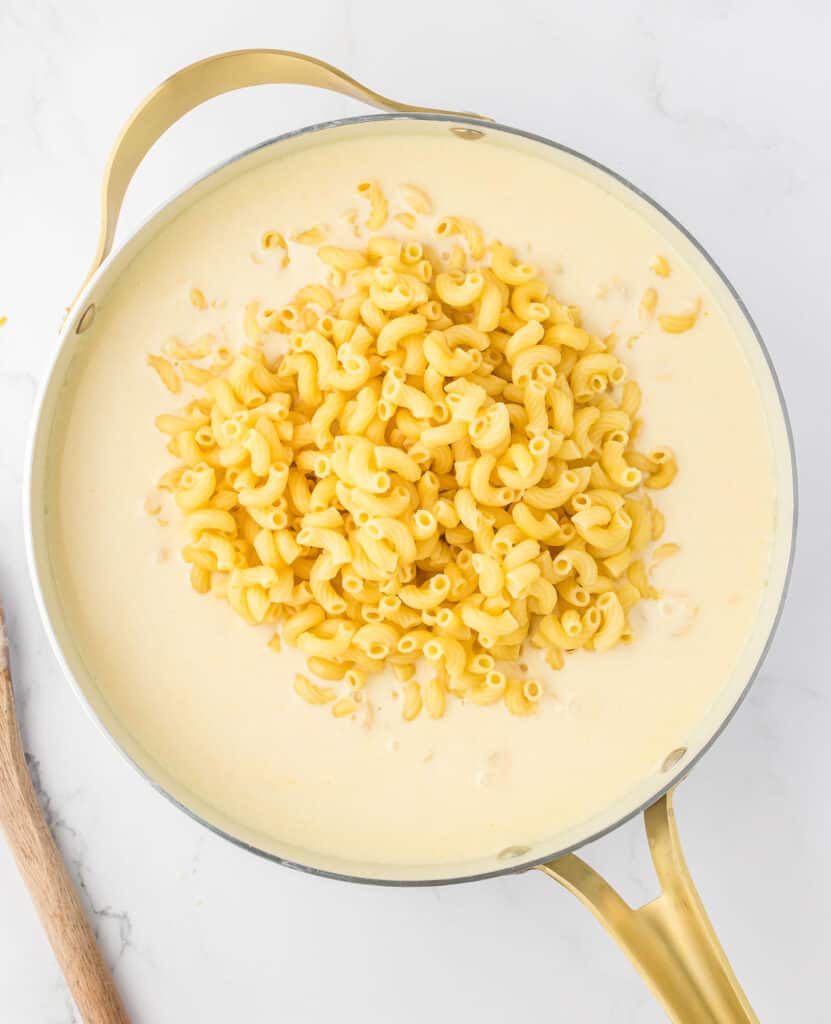 adding macaroni noodles to the cheese sauce