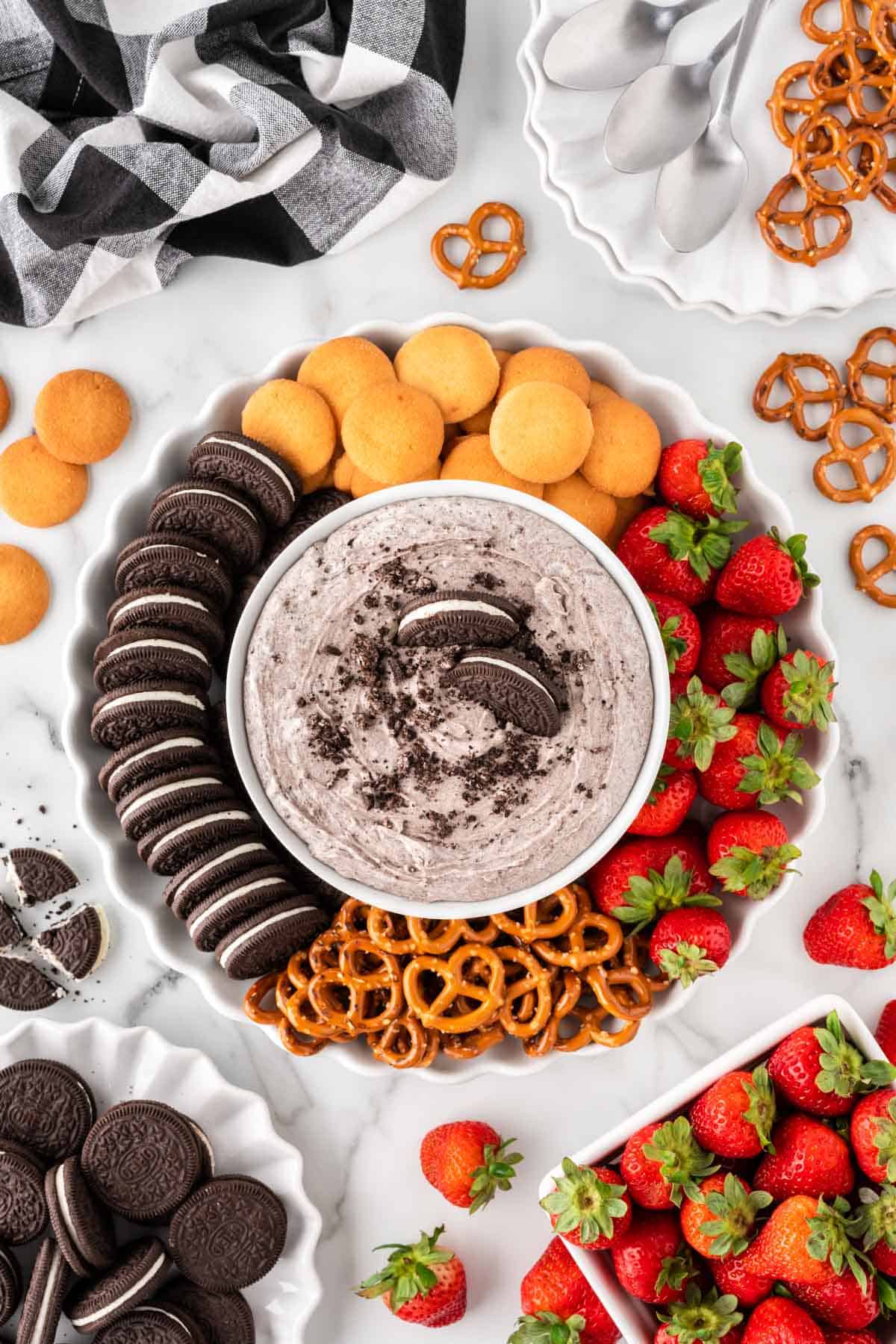 oreo dip on a platter with nilla wafers, oreos, strawberries, and pretzels for dipping