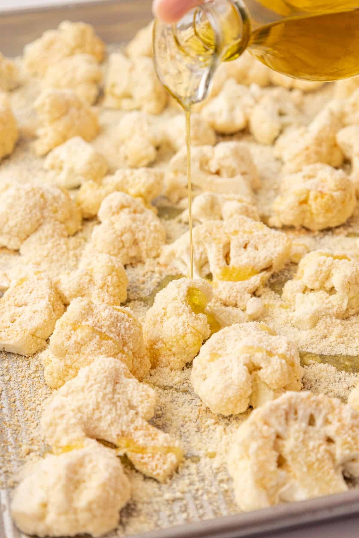 pouring olive oil onto the cauliflower florets