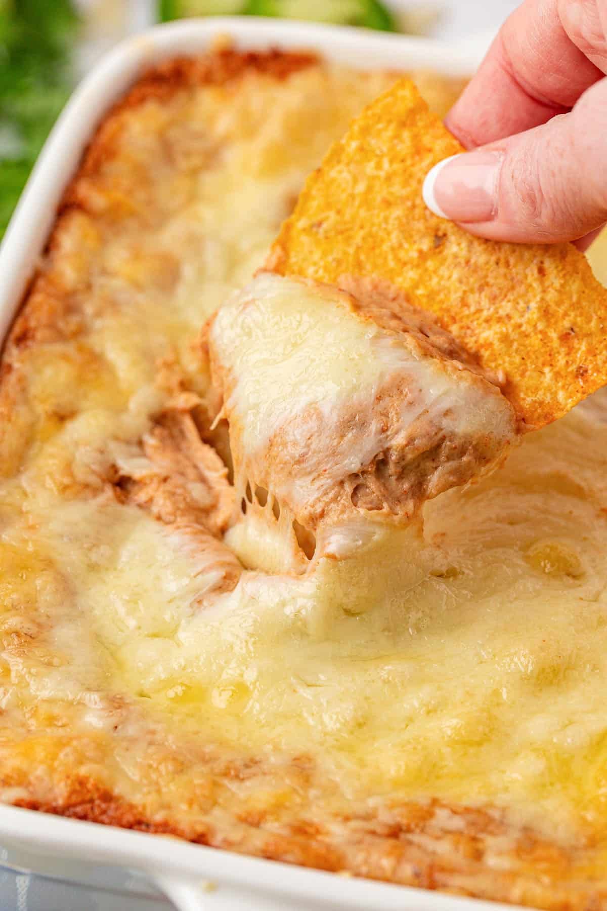 dipping a chip into cream cheese bean dip