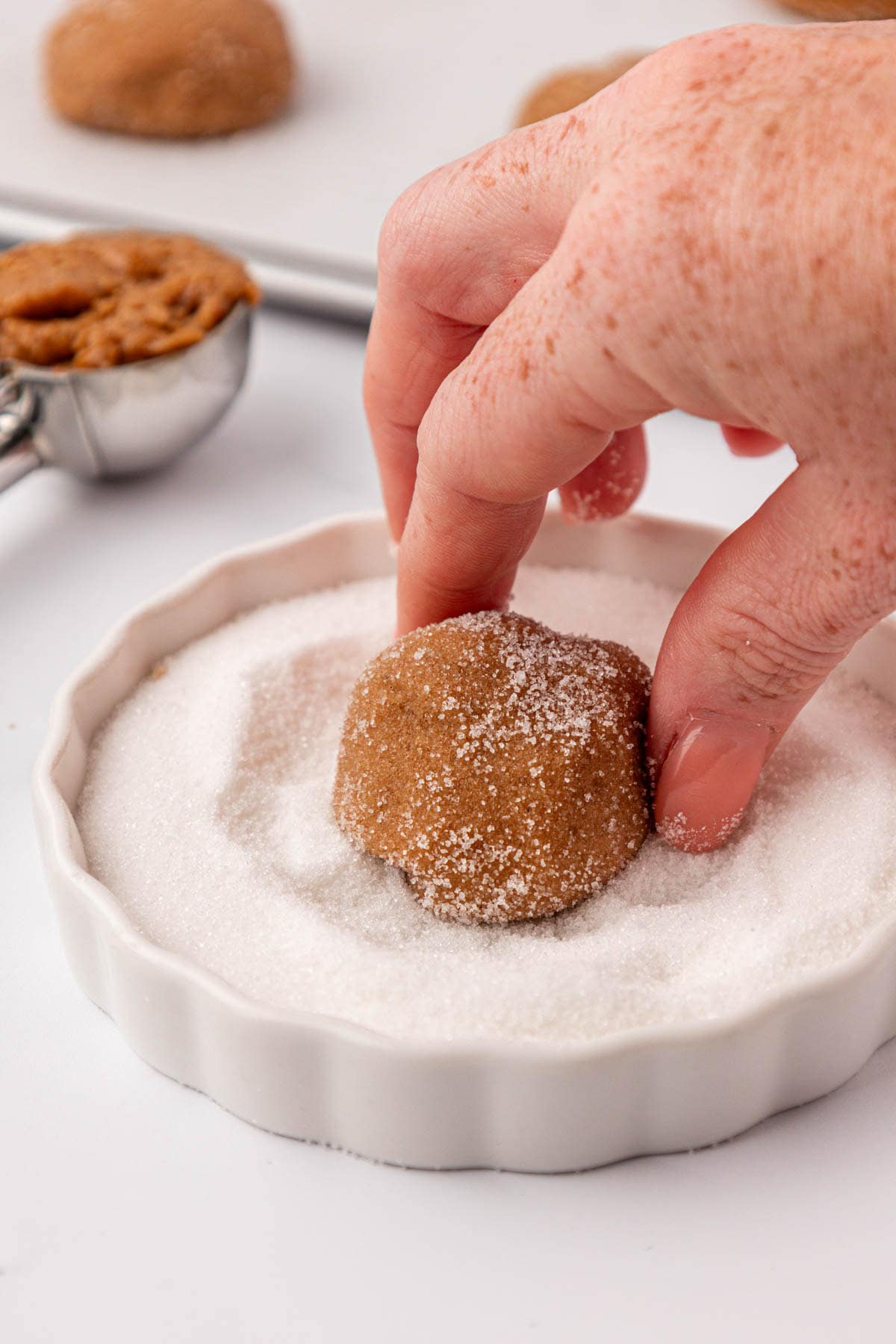 dipping a cookie dough ball into sugar