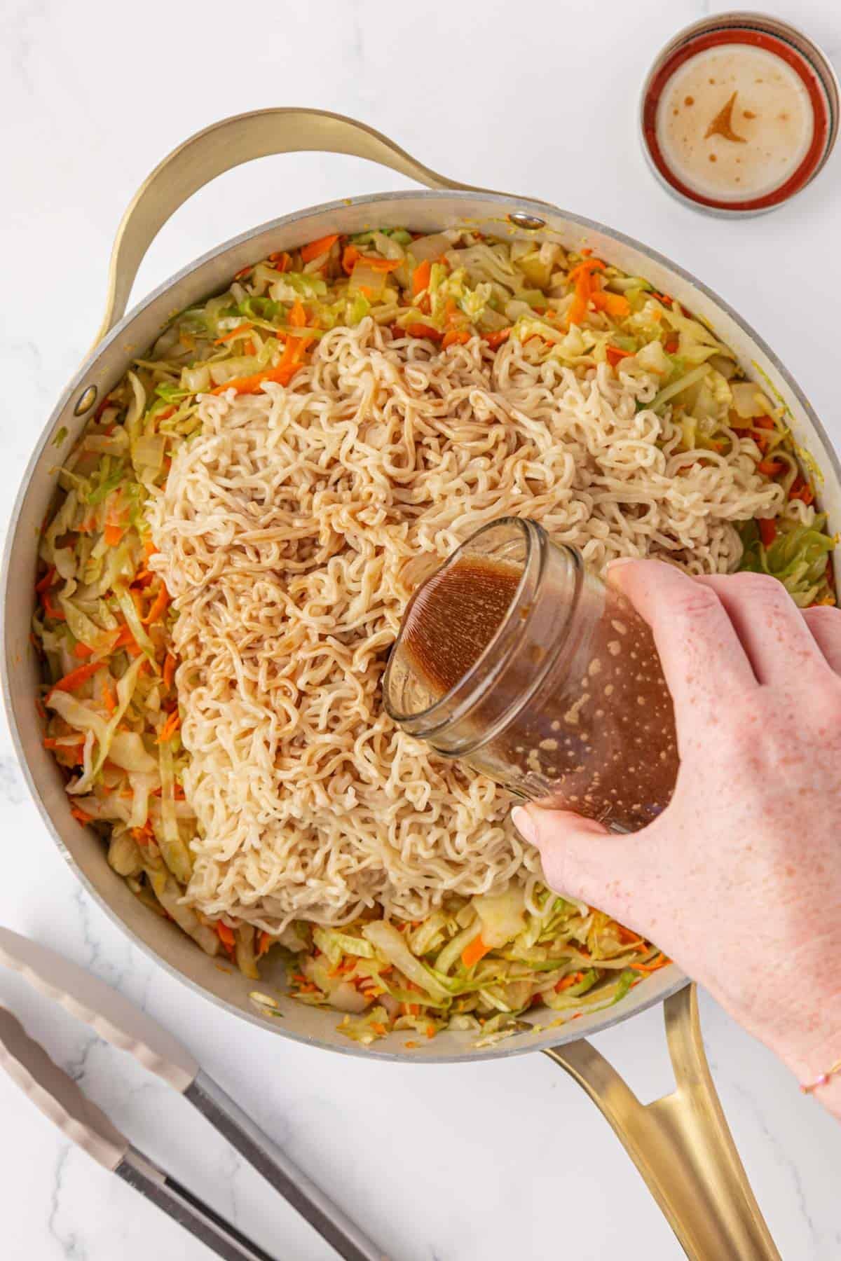 pouring stir fry sauce onto the ramen noodles
