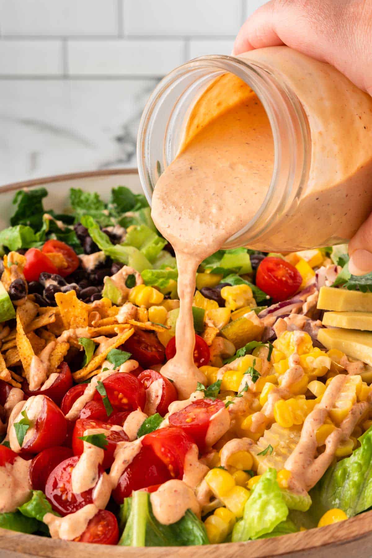 pouring southwest salad dressing over a salad