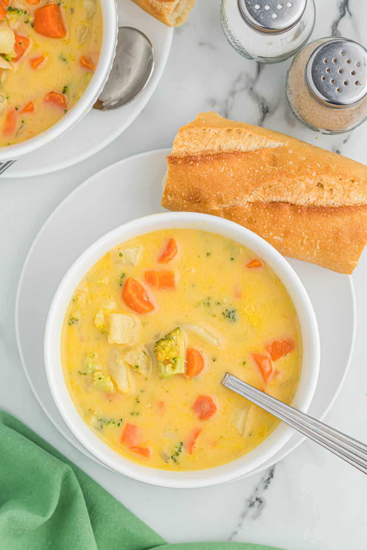 vegetable soup in a white bowl next to a baguette