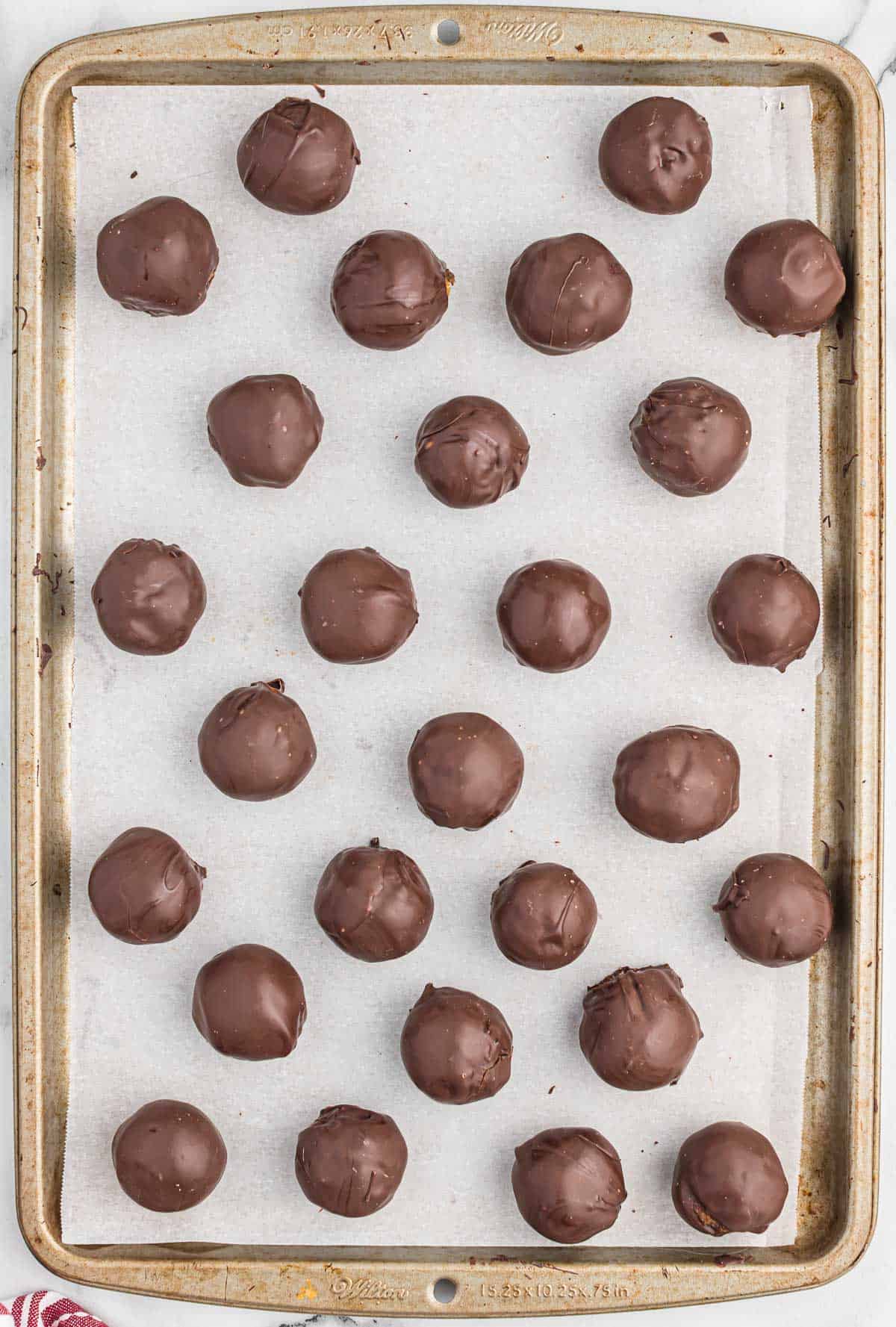 chocolate covered pecan balls on a baking sheet