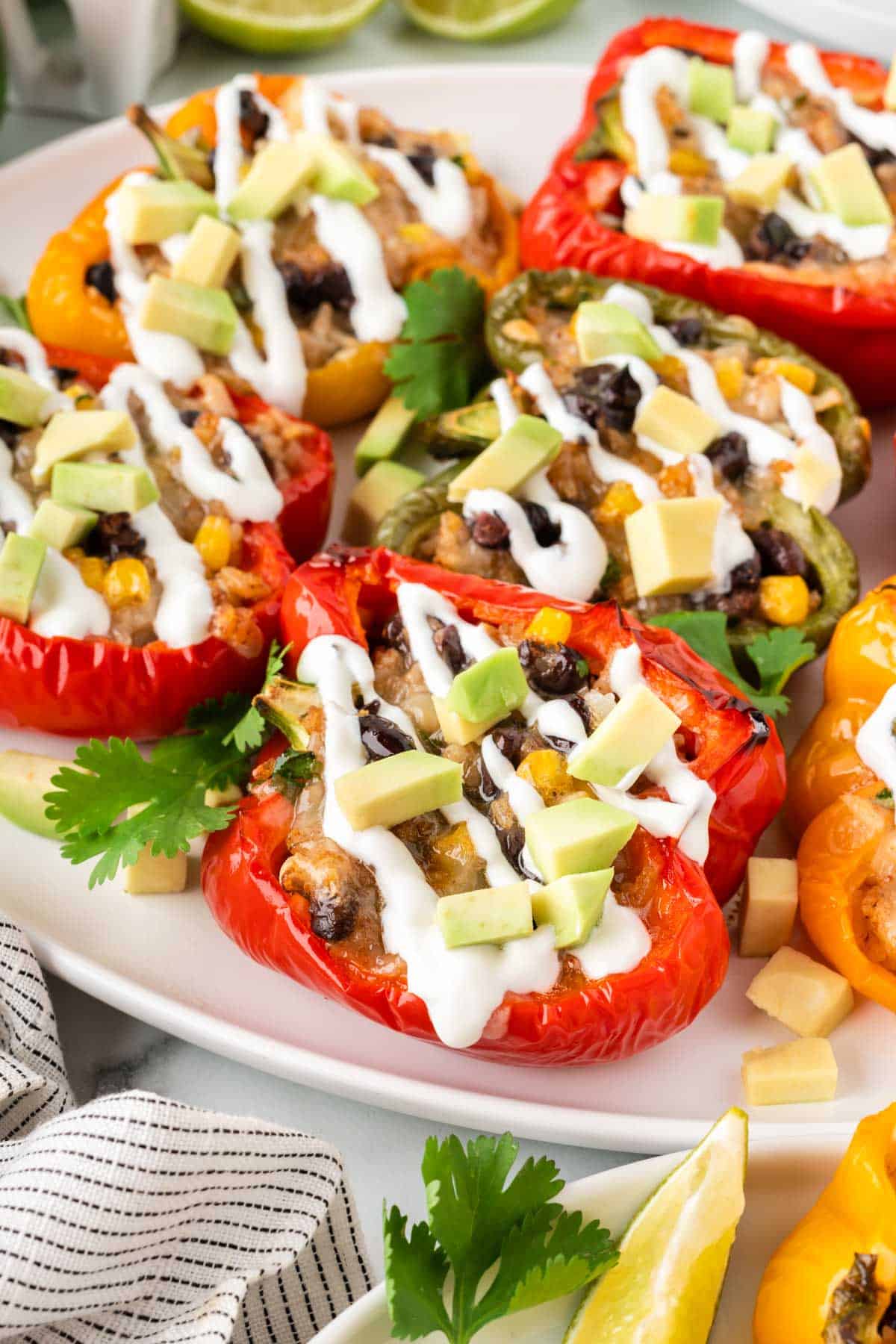 vegetarian stuffed peppers on a plate topped with sour cream and avocado pieces