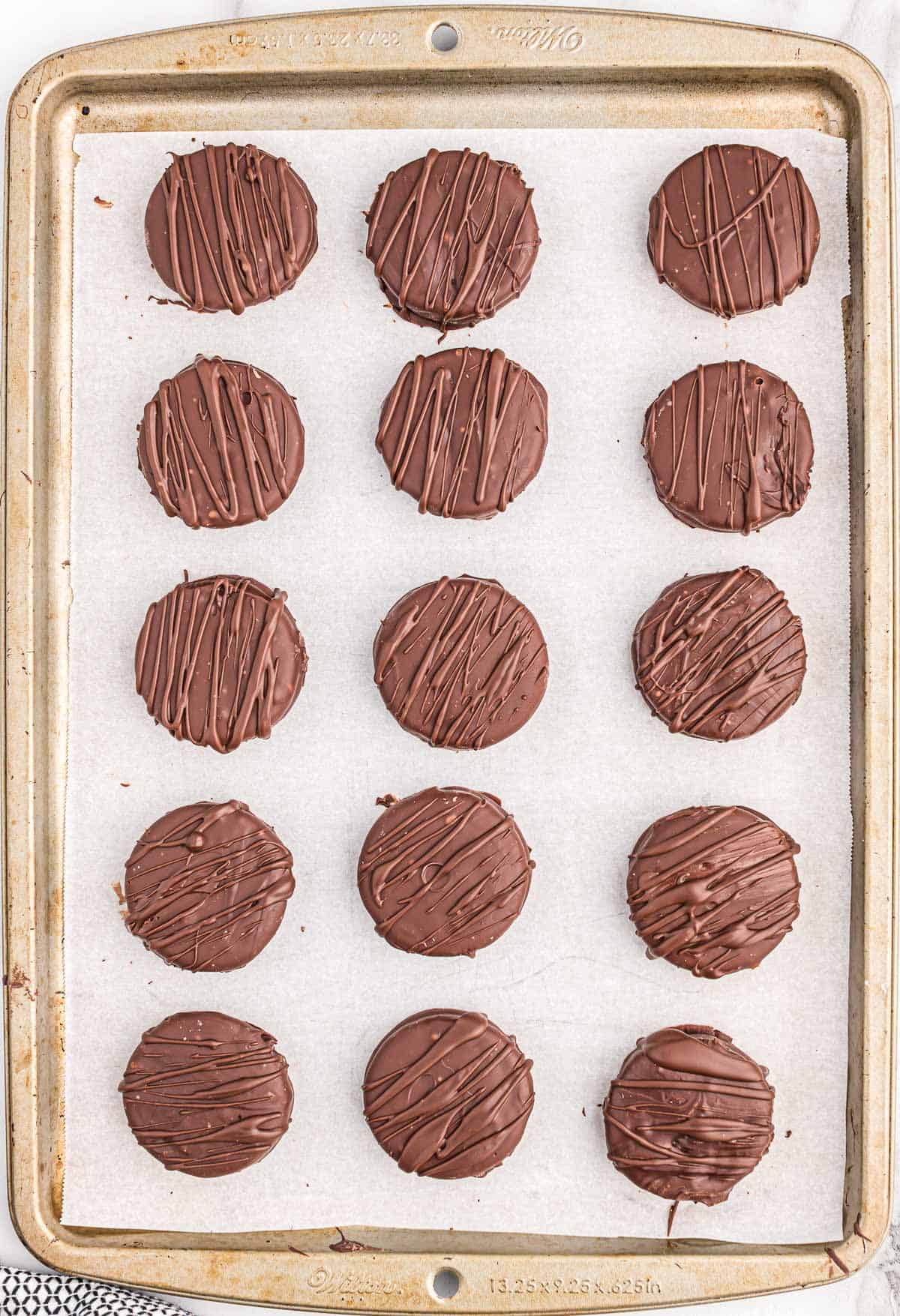 chocolate drizzled oreos on a baking sheet