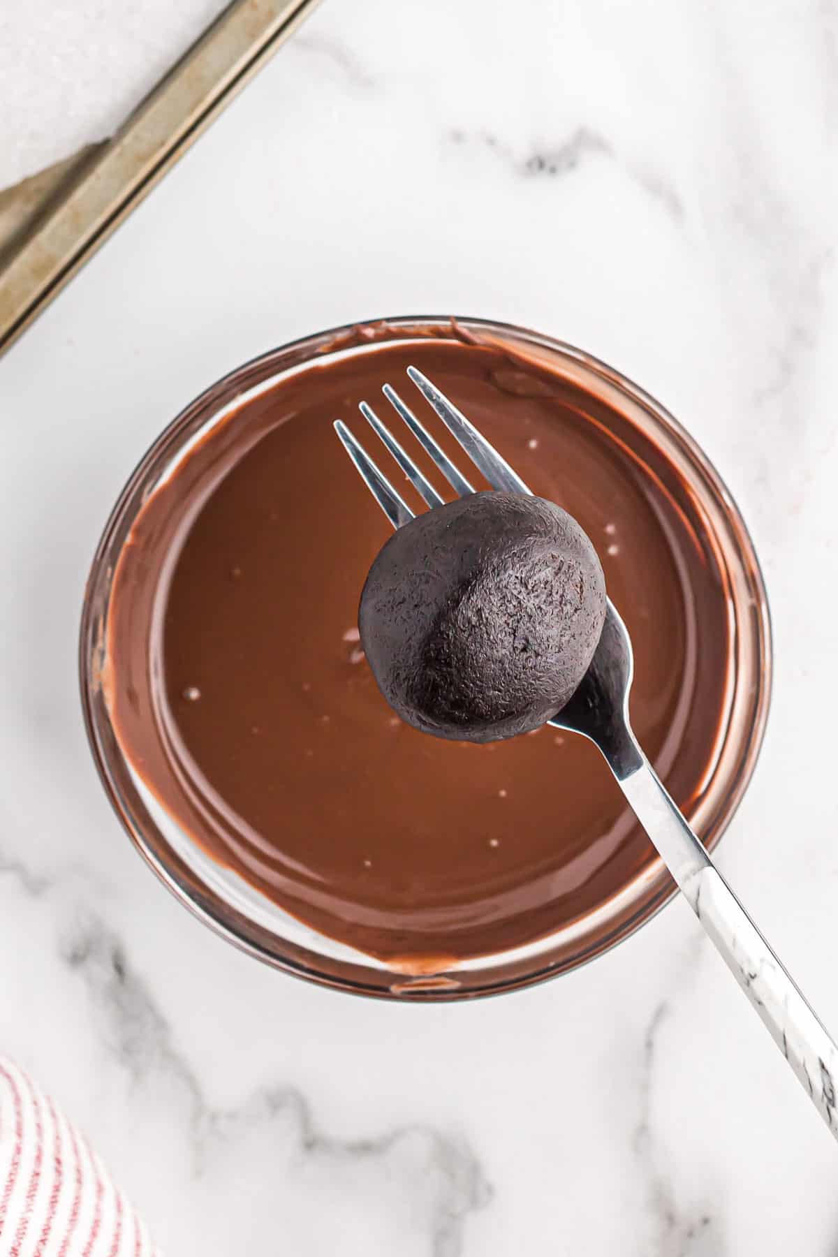 holding an oreo ball over melted dark chocolate