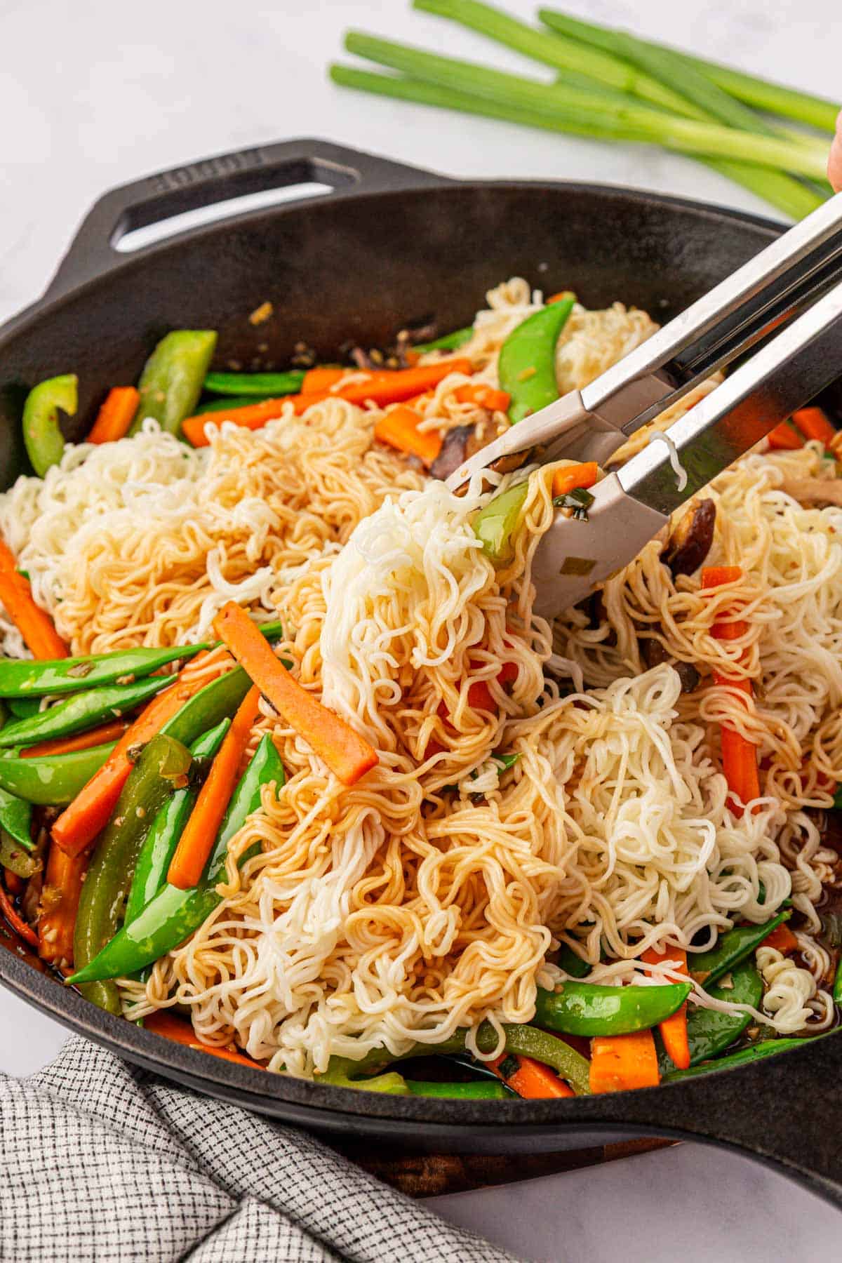 stirring the ramen noodles and stir fry sauce into the vegetables