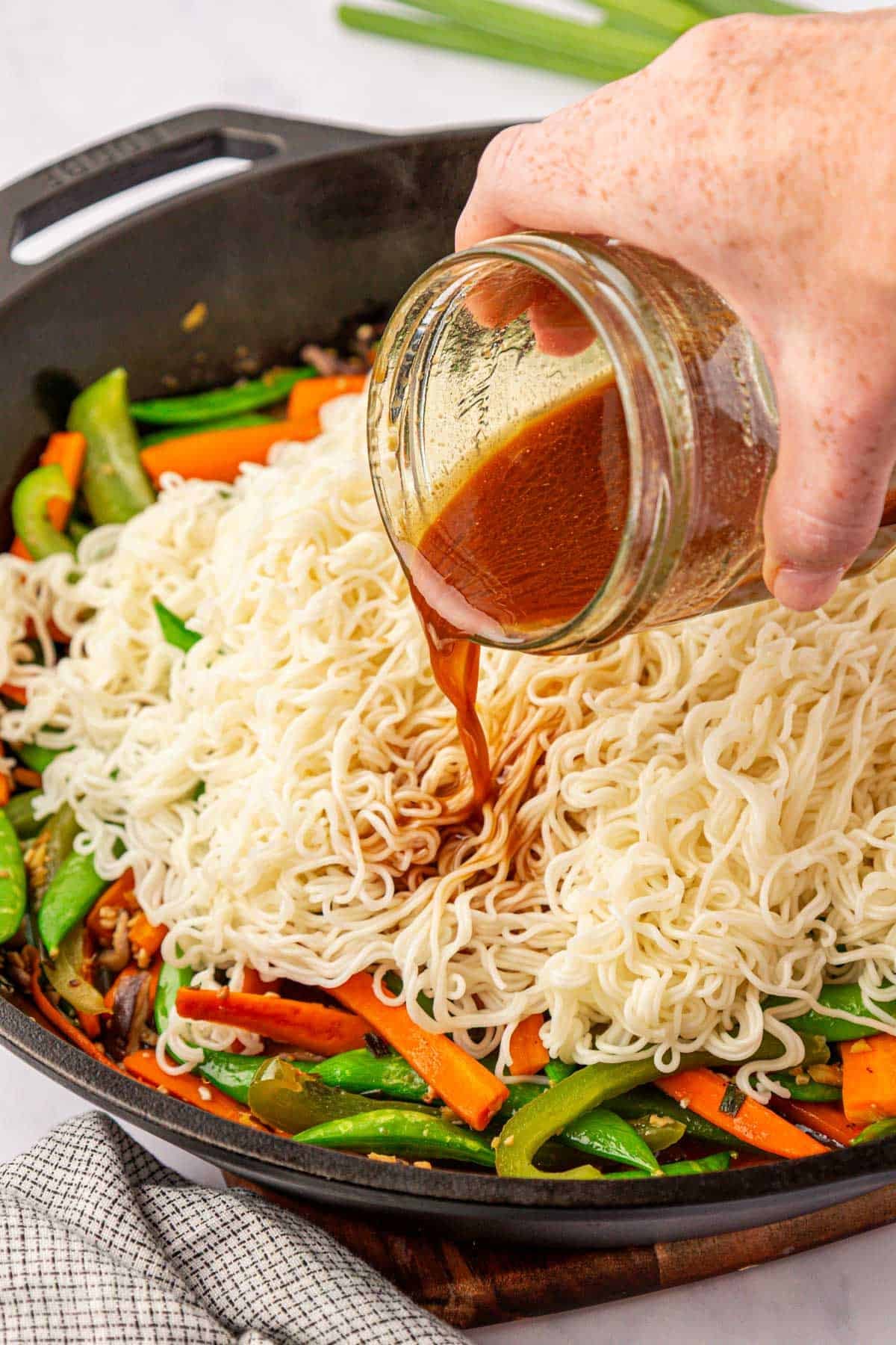 pouring stir fry sauce over ramen noodles