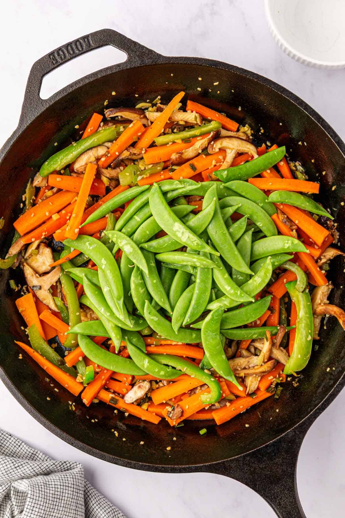 adding snap peas to the skillet
