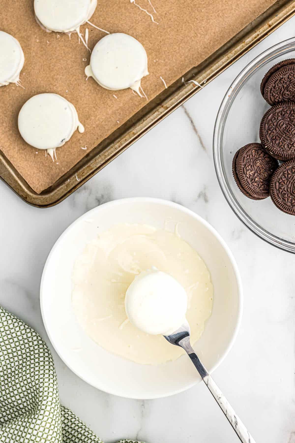 dipping an oreo into melted white chocolate