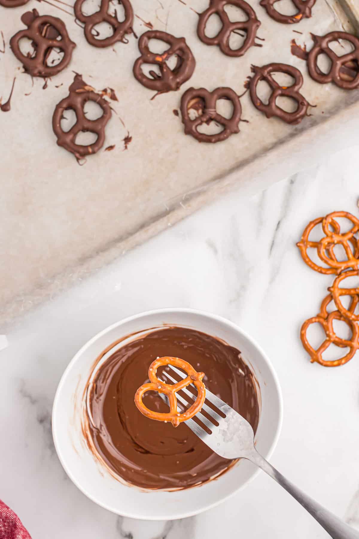 holding a pretzel over a small bowl of melted dark chocolate