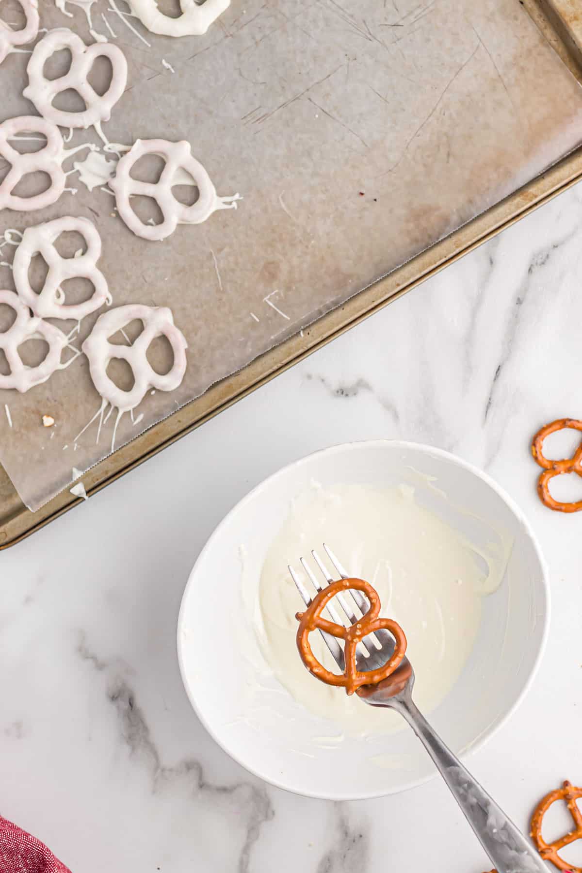holding a pretzel over a small bowl of melted white chocolate