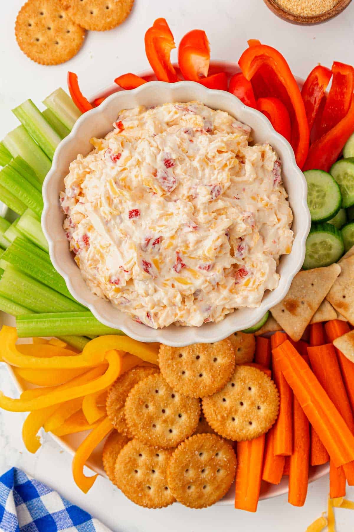 pimento cheese on a platter with crackers and cut up vegetables