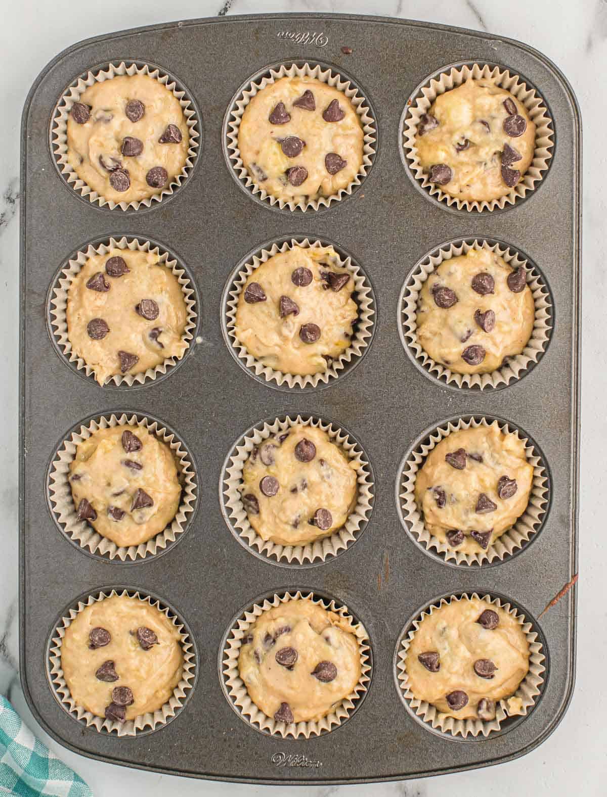 muffin tin filled with banana chocolate chip muffin batter