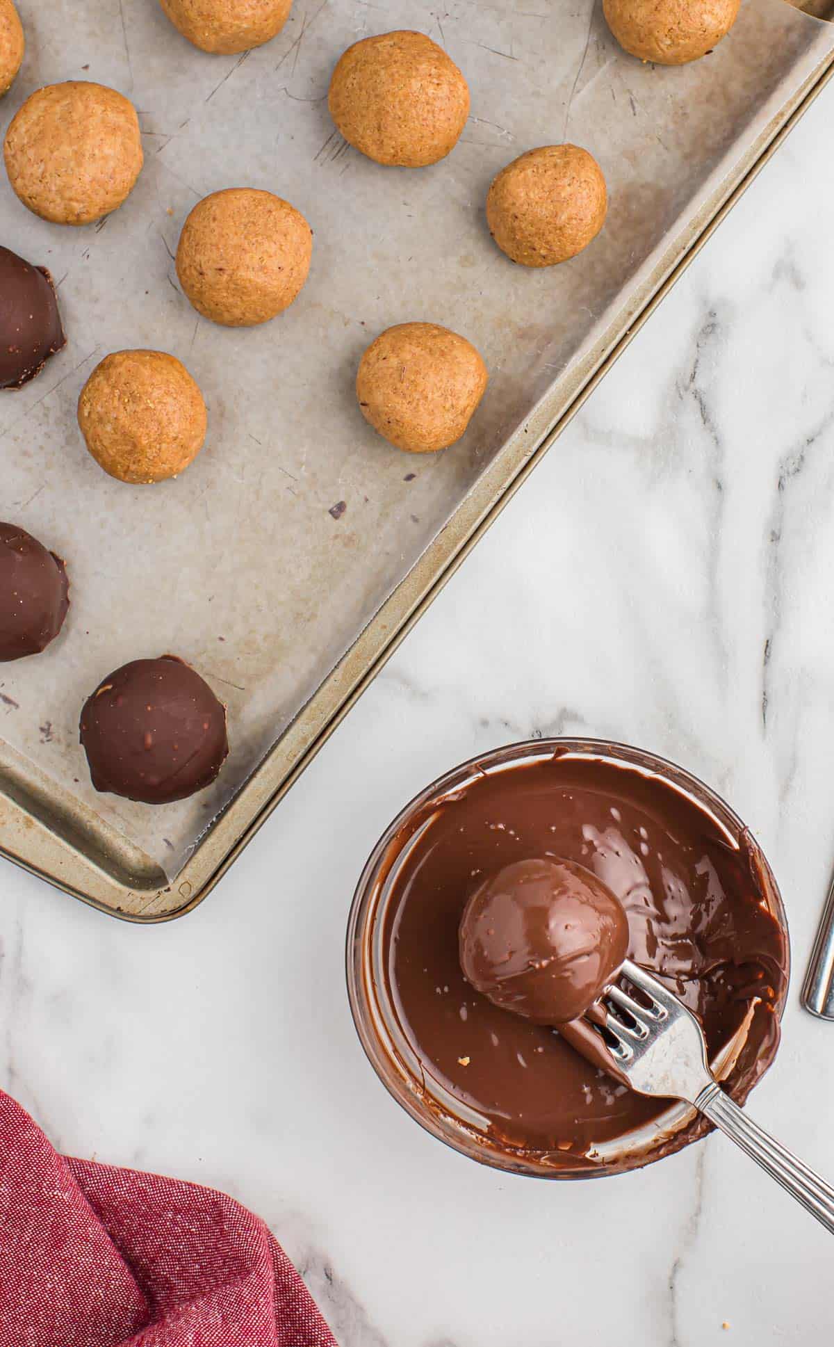 dipping a peanut butter ball into melted chocolate