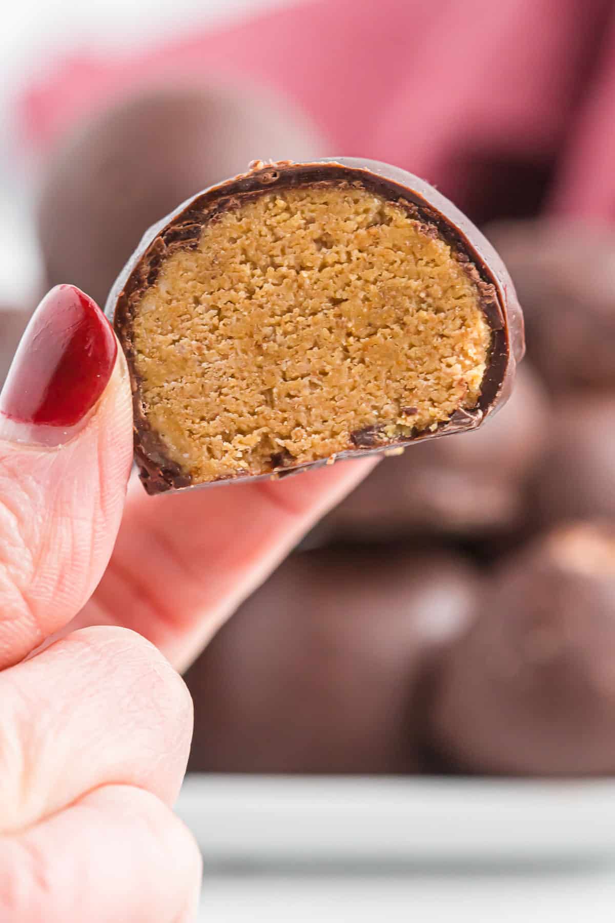 holding a peanut butter ball cut open to show the filling